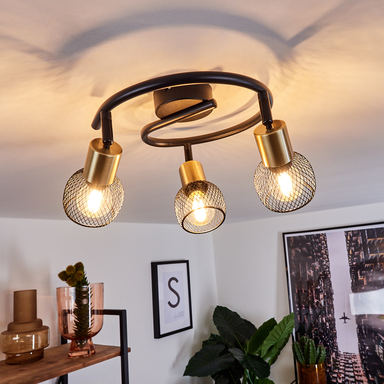 Moderne Deckenleuchte mit drei schwarzen Armen und goldenen Lampenschirmen.
