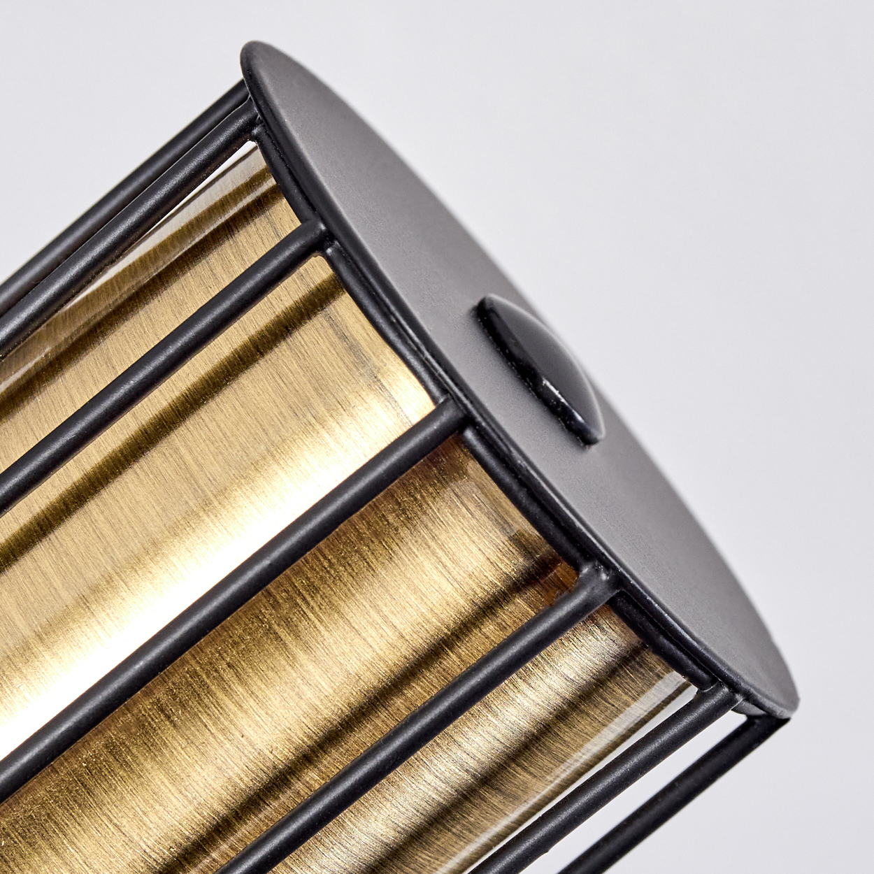 Ein schwarzer Metallkäfig umgibt ein goldfarbenes, gestreiftes Material.