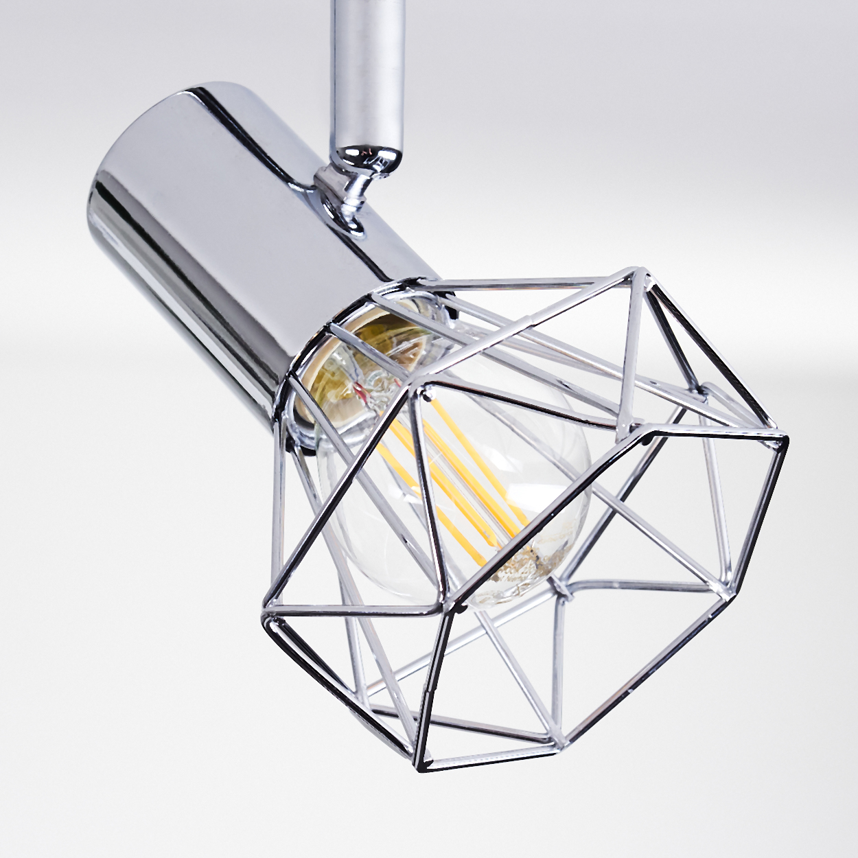 Eine glänzende Metalllampe mit einem geometrischen Käfig und einem sichtbaren Leuchtmittel.