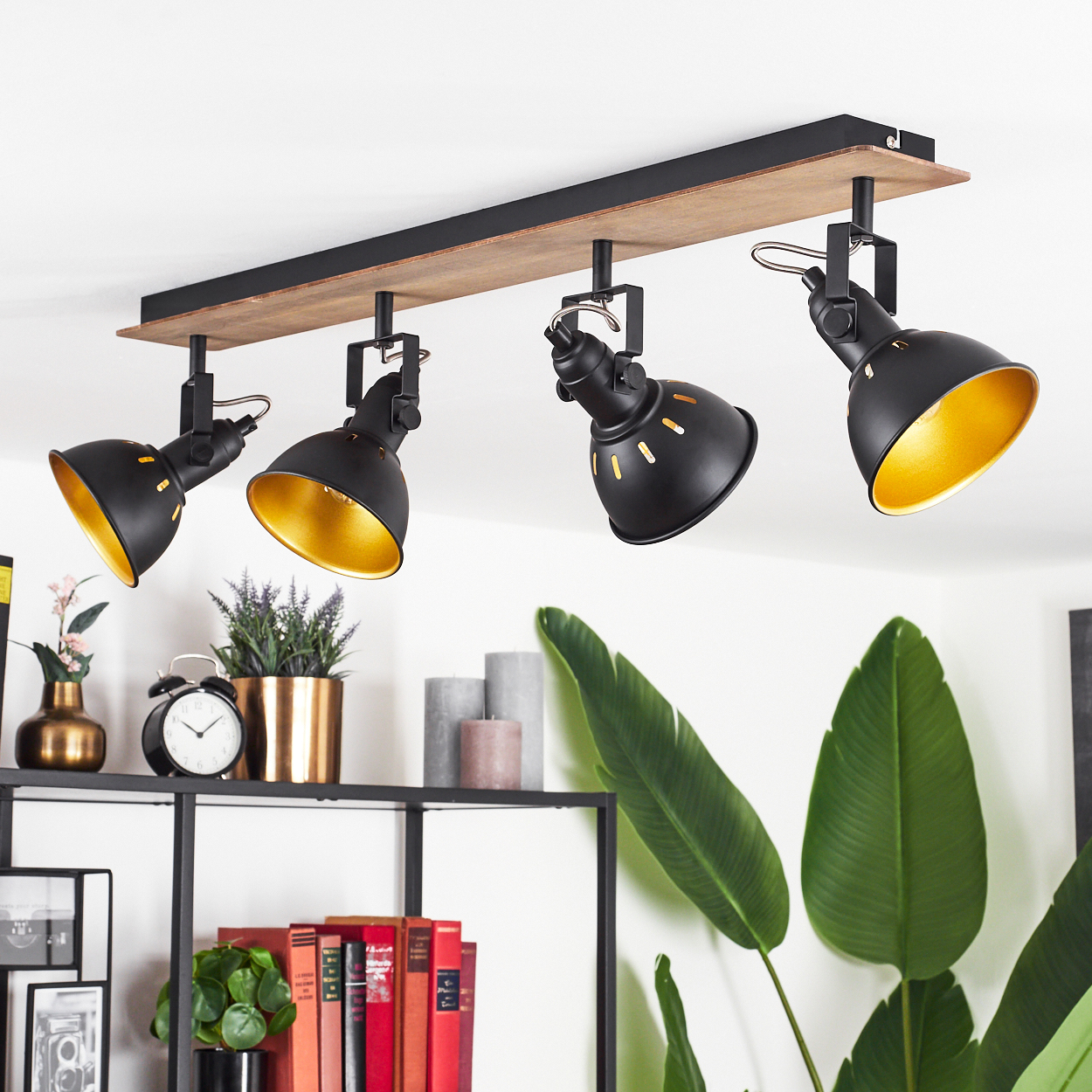 Schwarze Deckenleuchte mit vier verstellbaren Spots auf Holzbrett. Goldene Innenseiten.