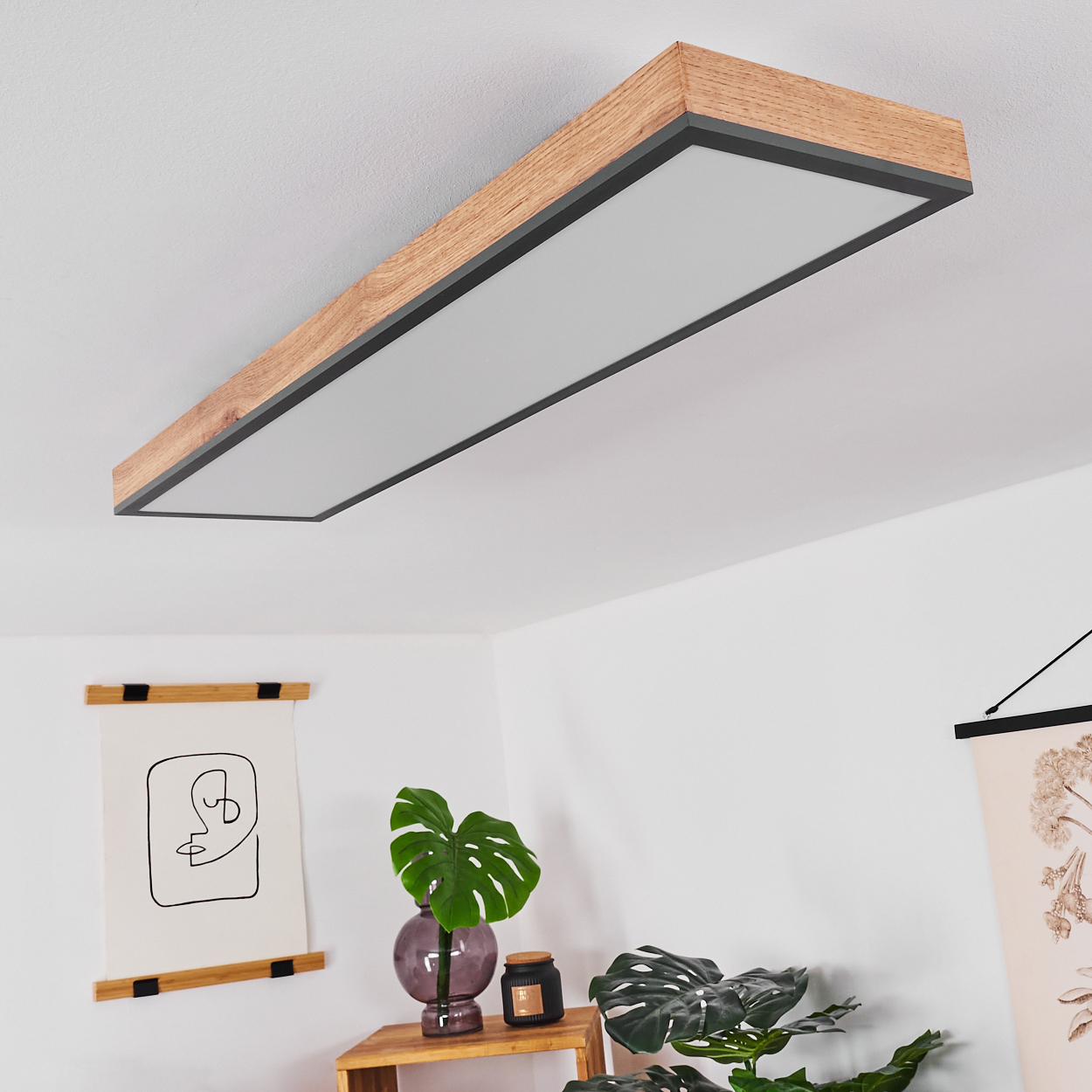 Moderne Deckenleuchte mit Holzrahmen und weißem Lichtdiffusor über Pflanzen.