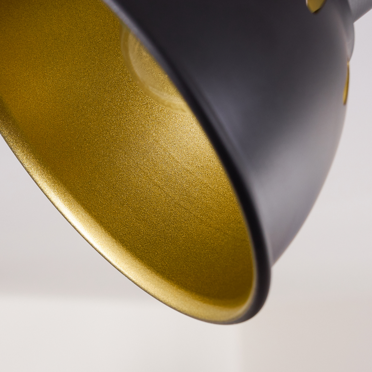 Ein schwarzer Lampenschirm mit goldener Innenseite, Nahaufnahme.