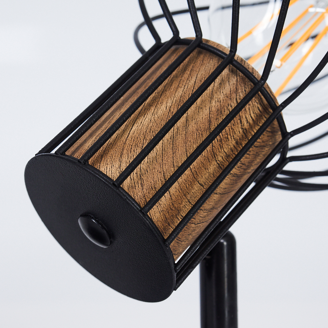 Eine Lampe mit Holzmaserung und schwarzem Drahtkäfig.