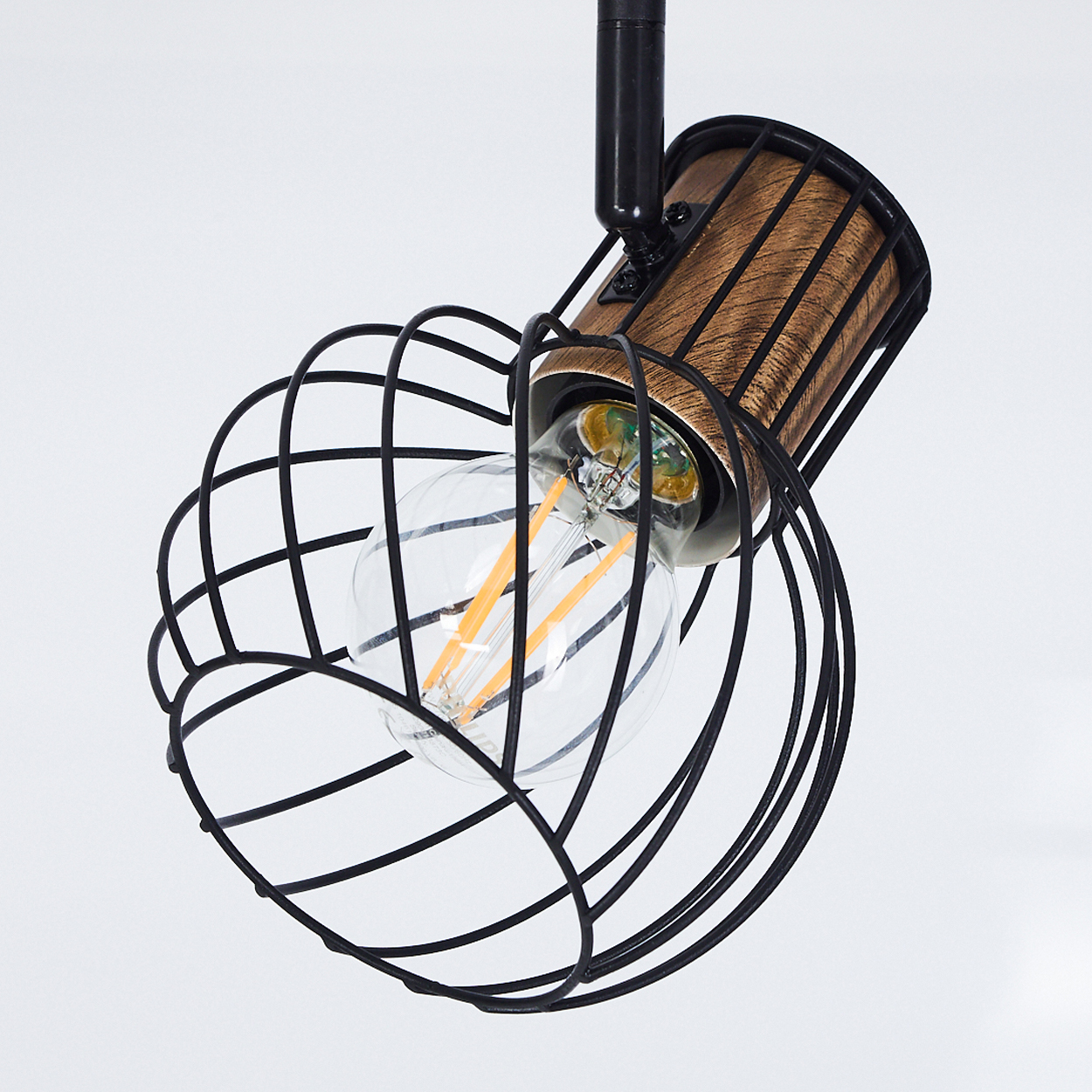 Eine Lampe mit schwarzem Drahtkäfig, Holzhülse und Glühfadenbirne.