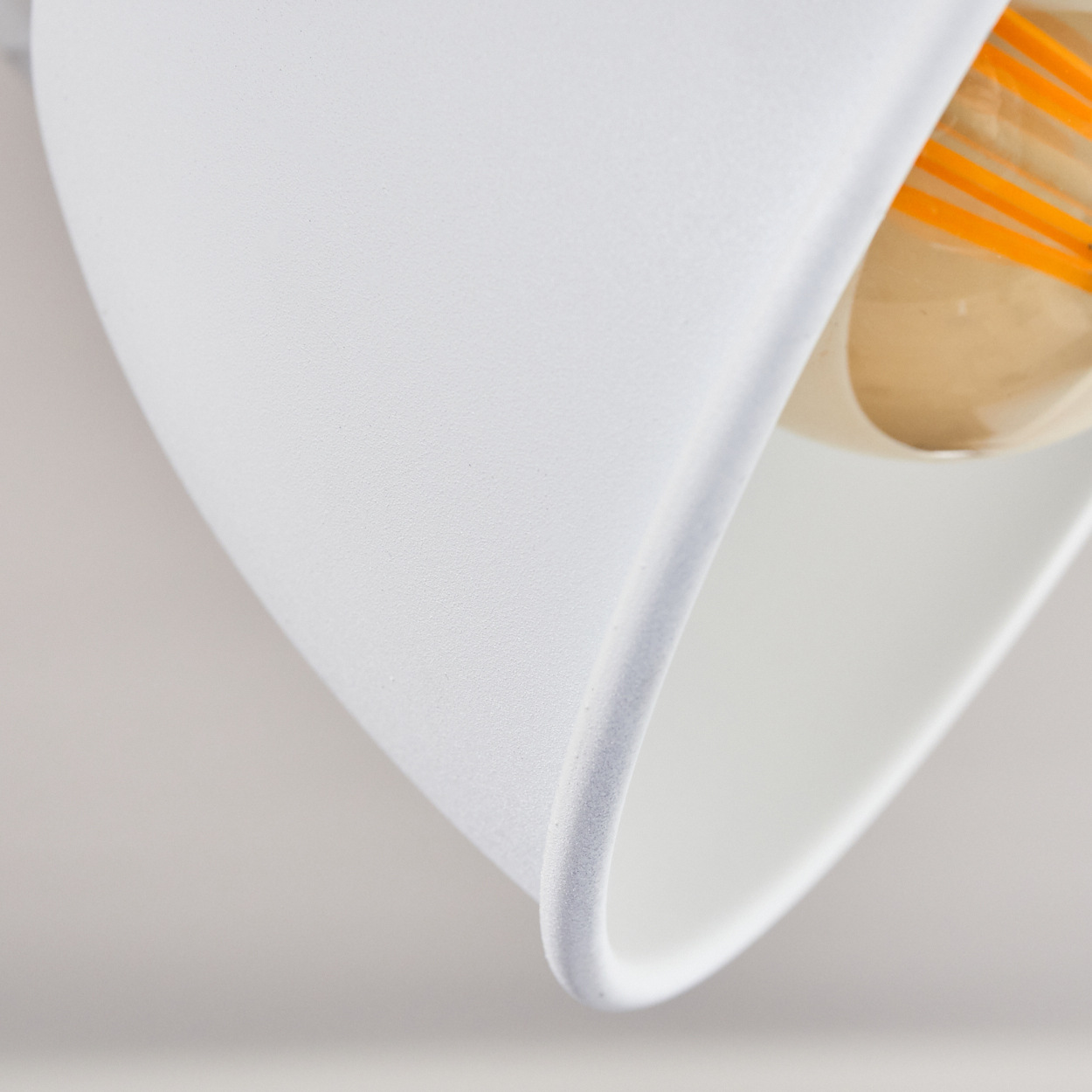 Nahaufnahme einer weißen Lampe mit orangefarbenen Glühfäden im Inneren.