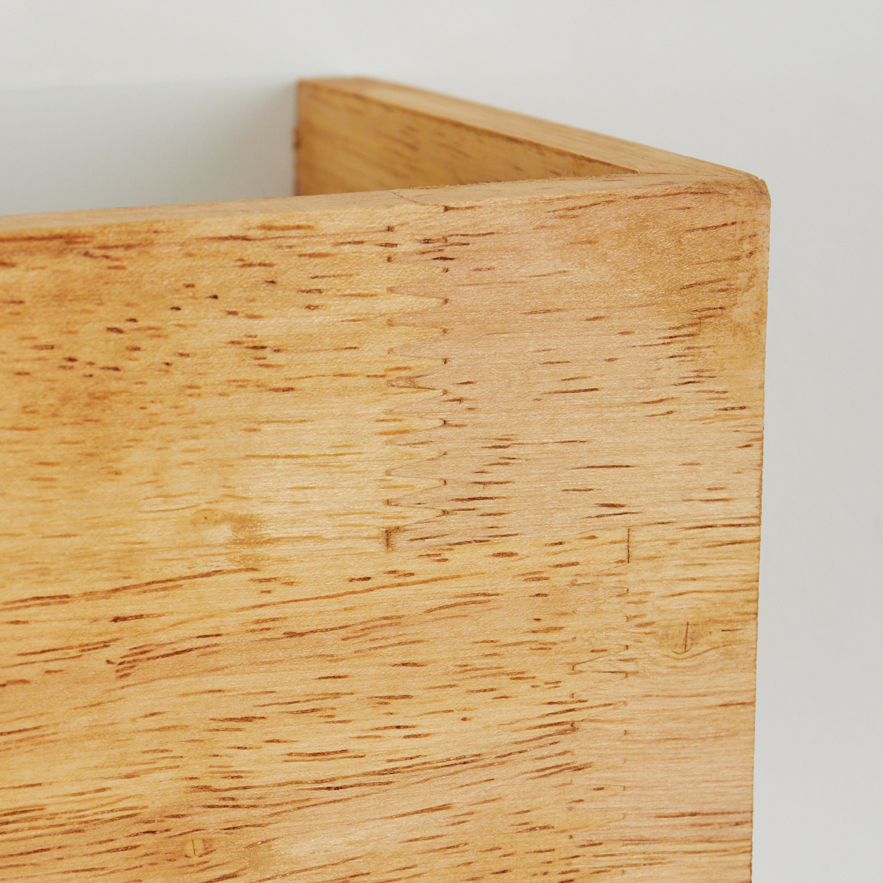 Nahaufnahme einer Ecke aus hellem Holz mit Maserung.