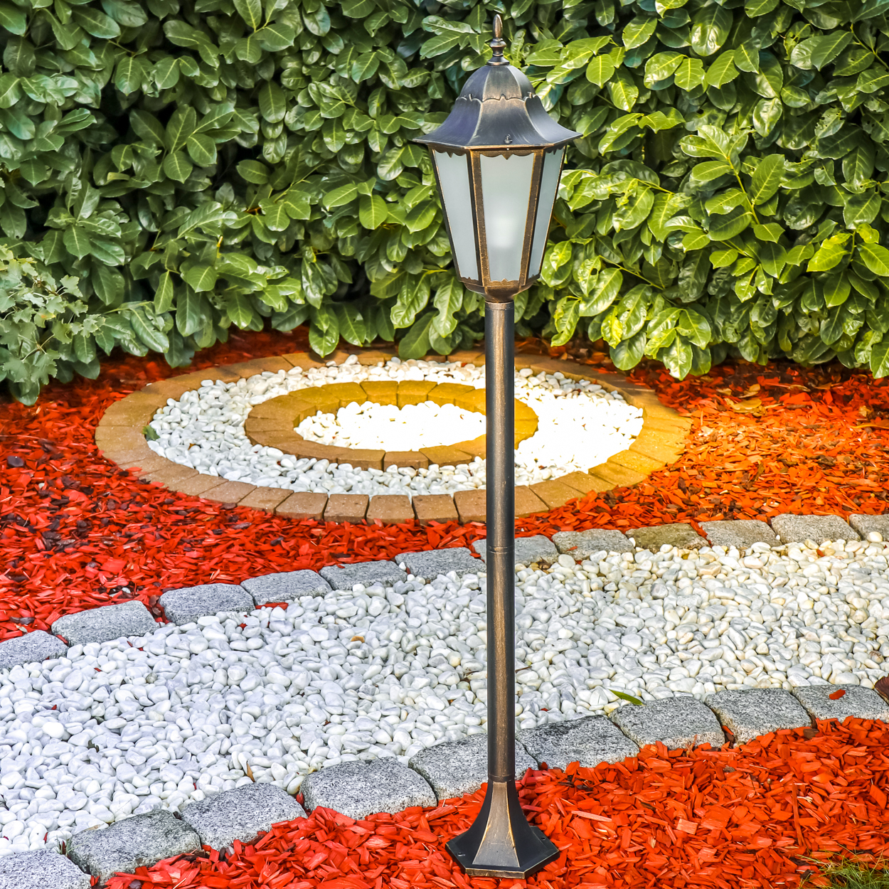 Ein Gartentor im Vordergrund vor einer dichten grünen Hecke.
