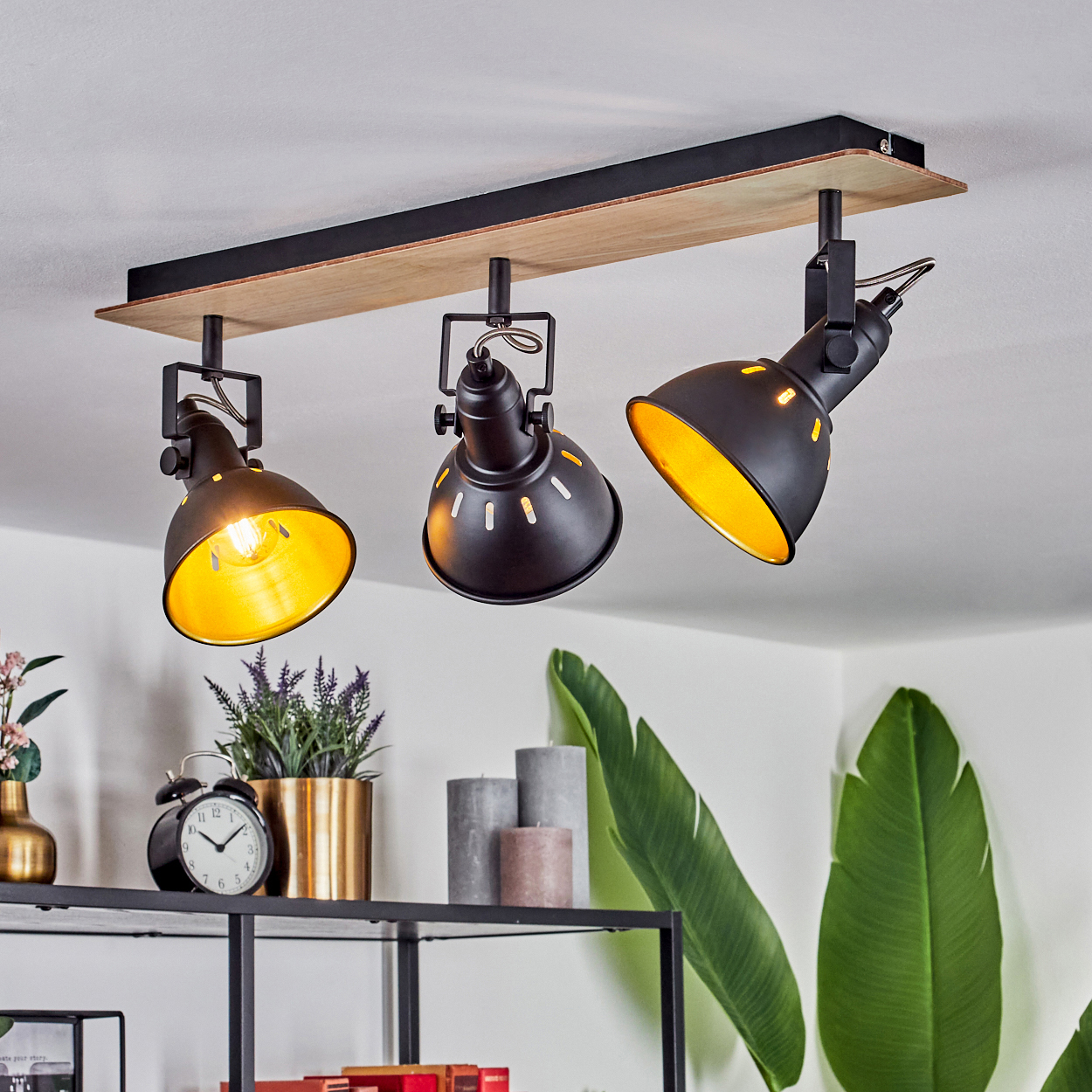 Schwarzer Deckenstrahler mit drei verstellbaren Lampen auf Holzbrett.