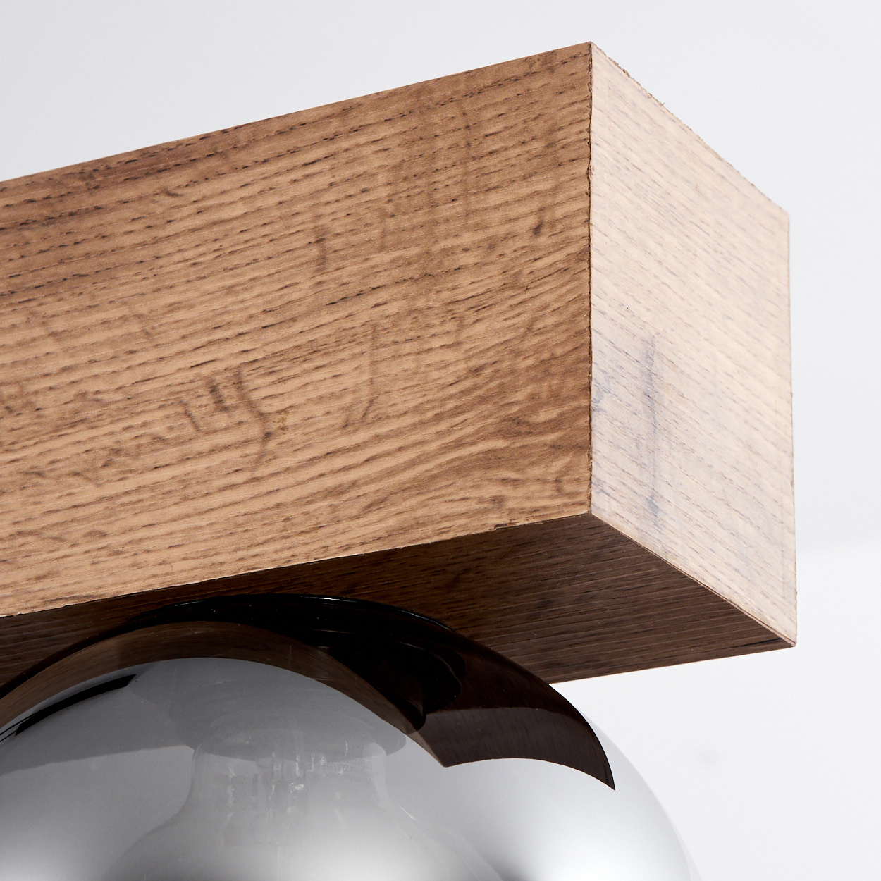 Holzbalken über einer glänzenden Kugel auf weißem Hintergrund.