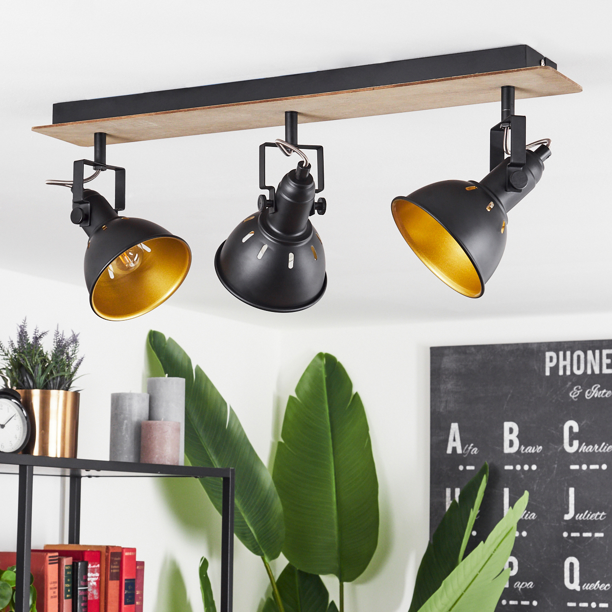 Drei schwarze Lampen mit goldenem Innerem an einem Holzbalken.