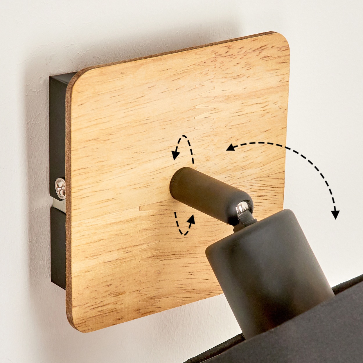 Ein schwarzer Lampenarm mit Holzplatte an einer weißen Wand. Pfeile zeigen Drehrichtung.