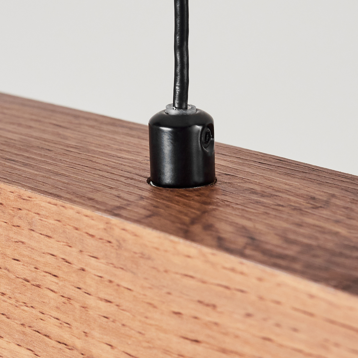 Ein schwarzes Kabel führt in eine schwarze Fassung auf einem Holzblock.