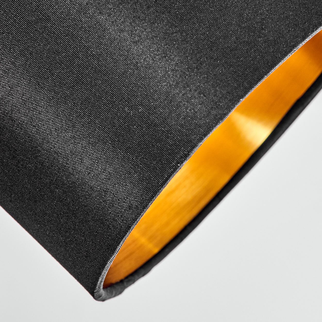 Schwarzer Lampenschirm mit goldener Innenseite im Detail.
