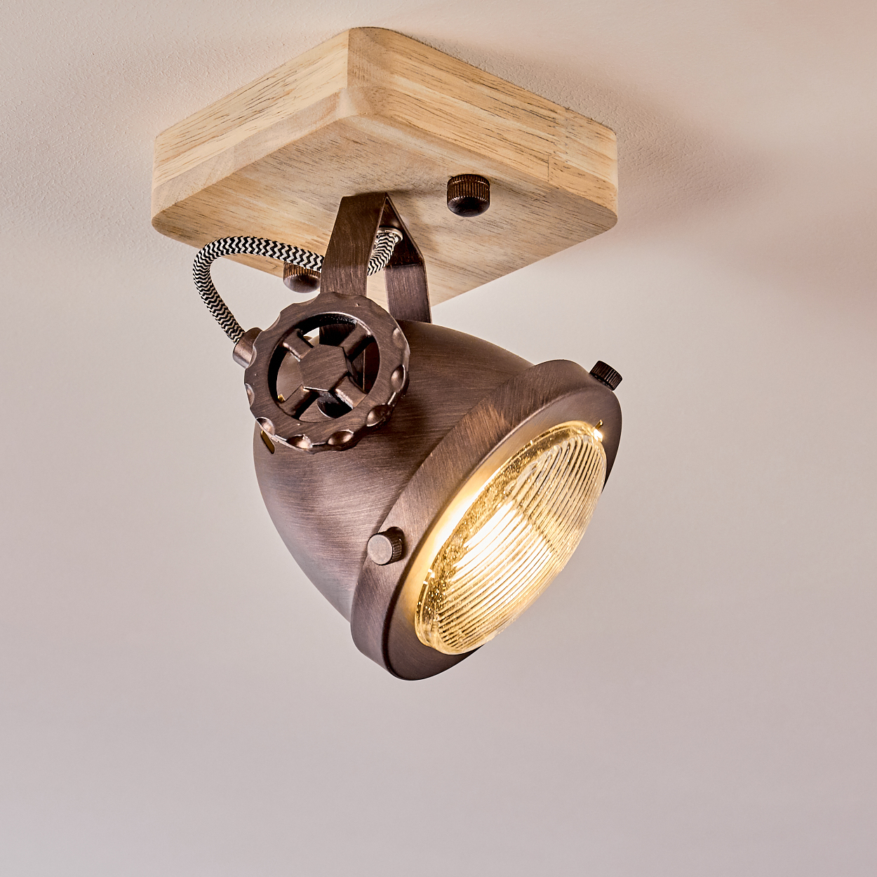 Ein Deckenstrahler mit Holzsockel und bronzefarbener Lampe.