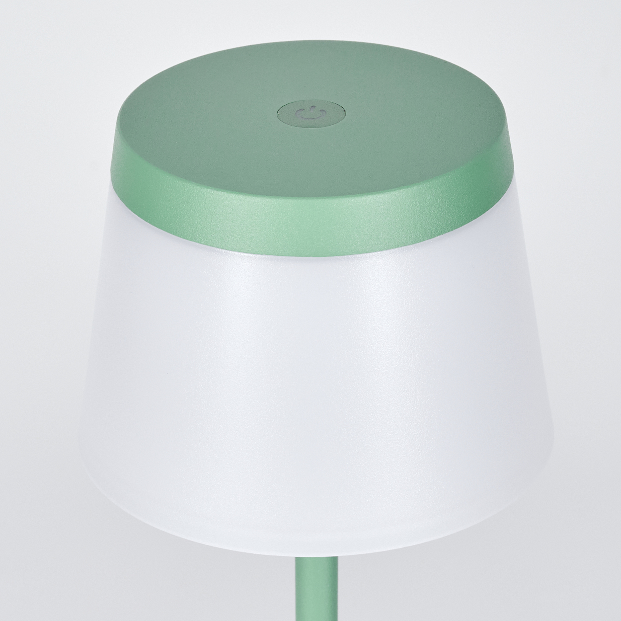Eine grüne Lampe mit weißem Lampenschirm und Power-Symbol auf dem Deckel.