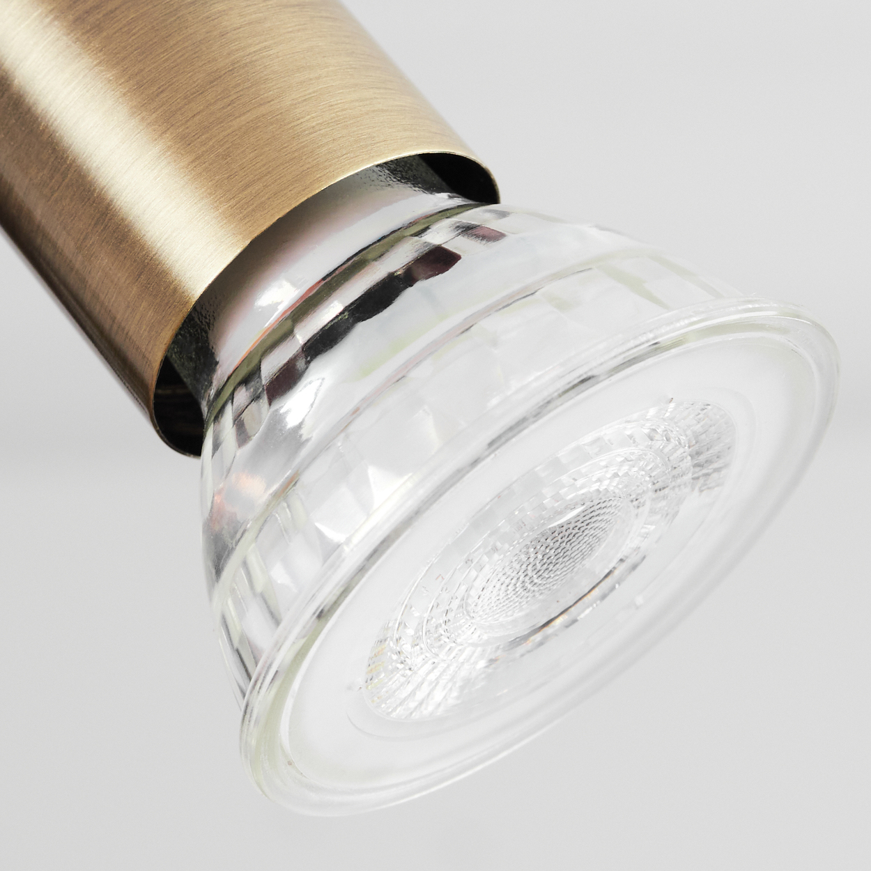 Nahaufnahme eines modernen LED-Spots mit Messing-Finish und klarer Glaslinse.