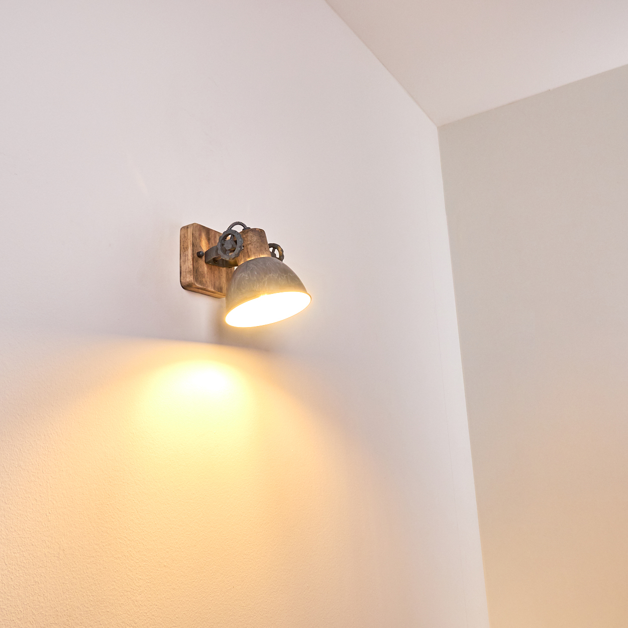 Ein Wandstrahler mit Holzsockel und Metallschirm leuchtet hell.