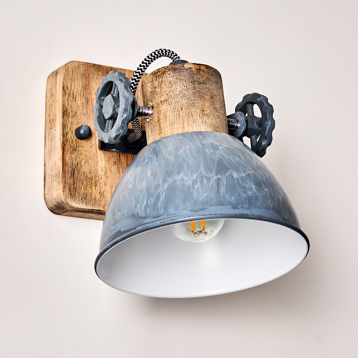 Wandleuchte mit Holzsockel, grauer Metallschirm und dekorativen Rädern.
