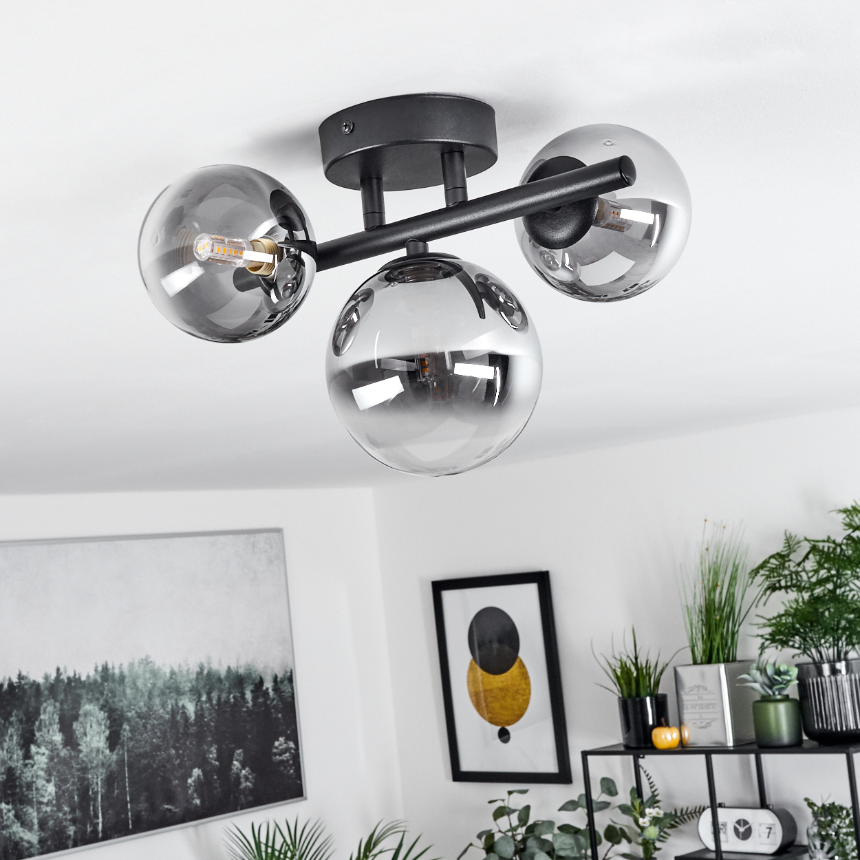 Moderne Deckenleuchte mit drei rauchgrauen Glaskugeln und schwarzem Metallgestell.