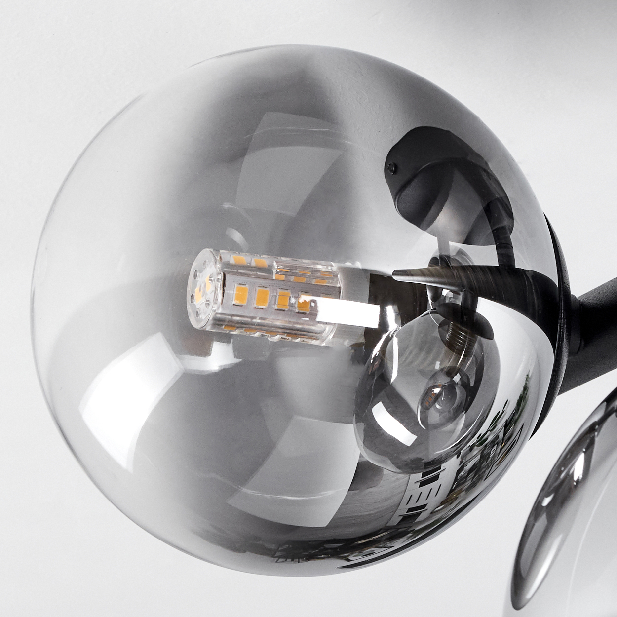 Naheinstellung einer runden, rauchfarbenen Glaslampe mit einer LED-Birne.