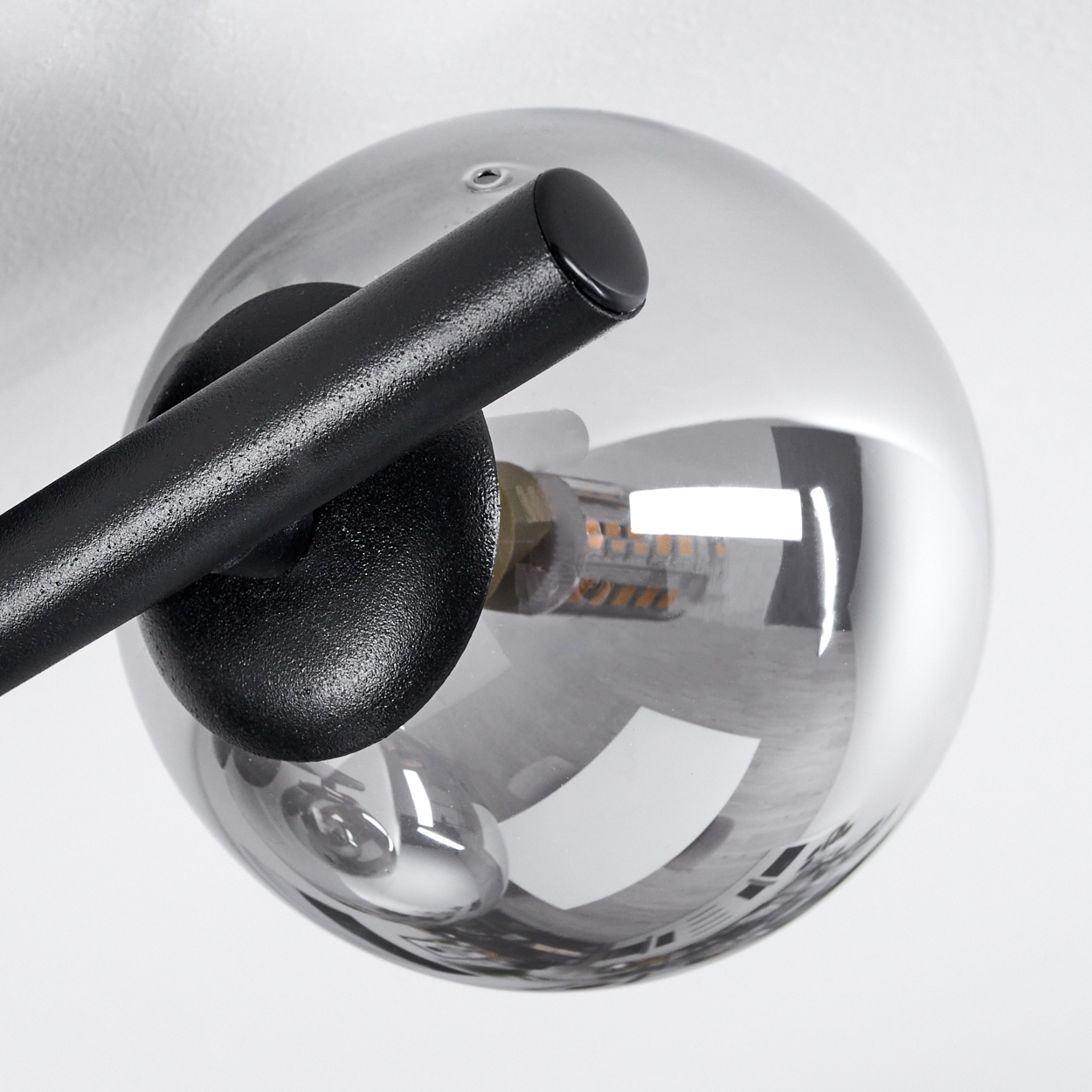Schwarzer Metallarm mit Glaskugel und sichtbarer Glühbirne.