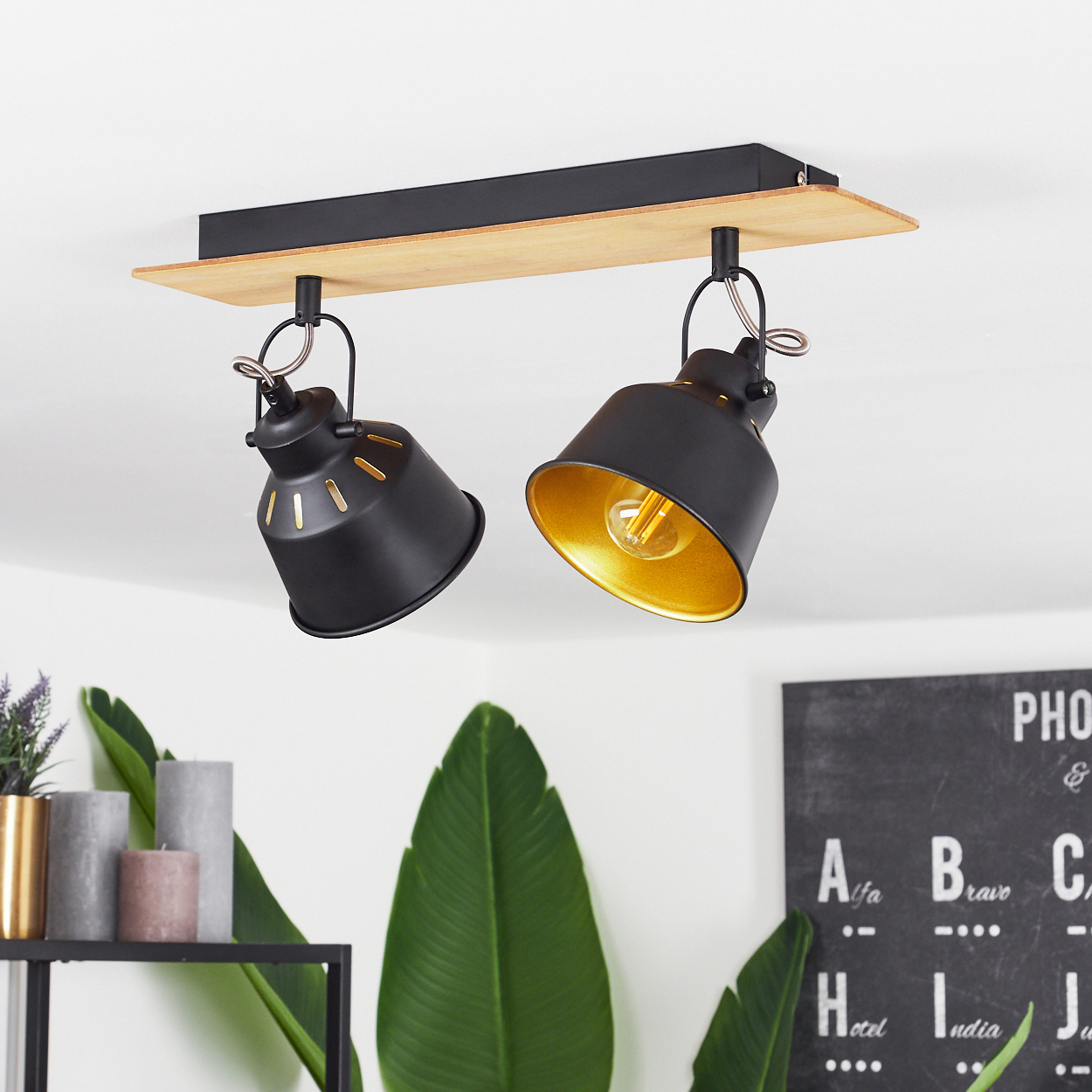 Zwei schwarze Lampenschirme mit goldenem Inneren hängen an Holzbrett.