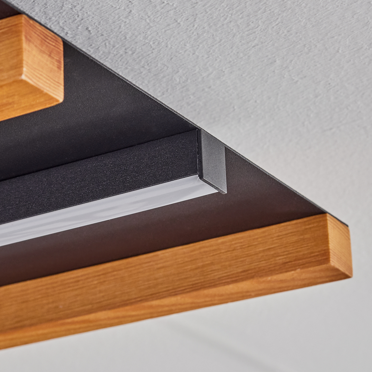 Ein moderner Deckenleuchter mit Holz- und Metallelementen und integriertem Lichtstreifen.