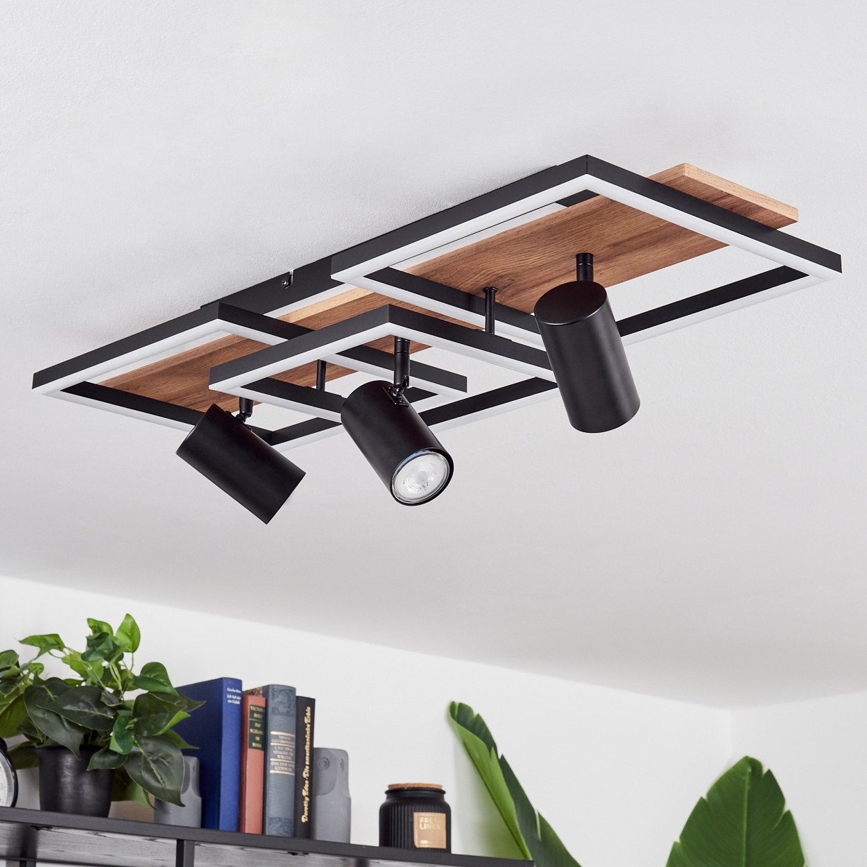 Schwarzer Deckenstrahler mit Holzdetails und weißen Rahmen auf weißer Decke.