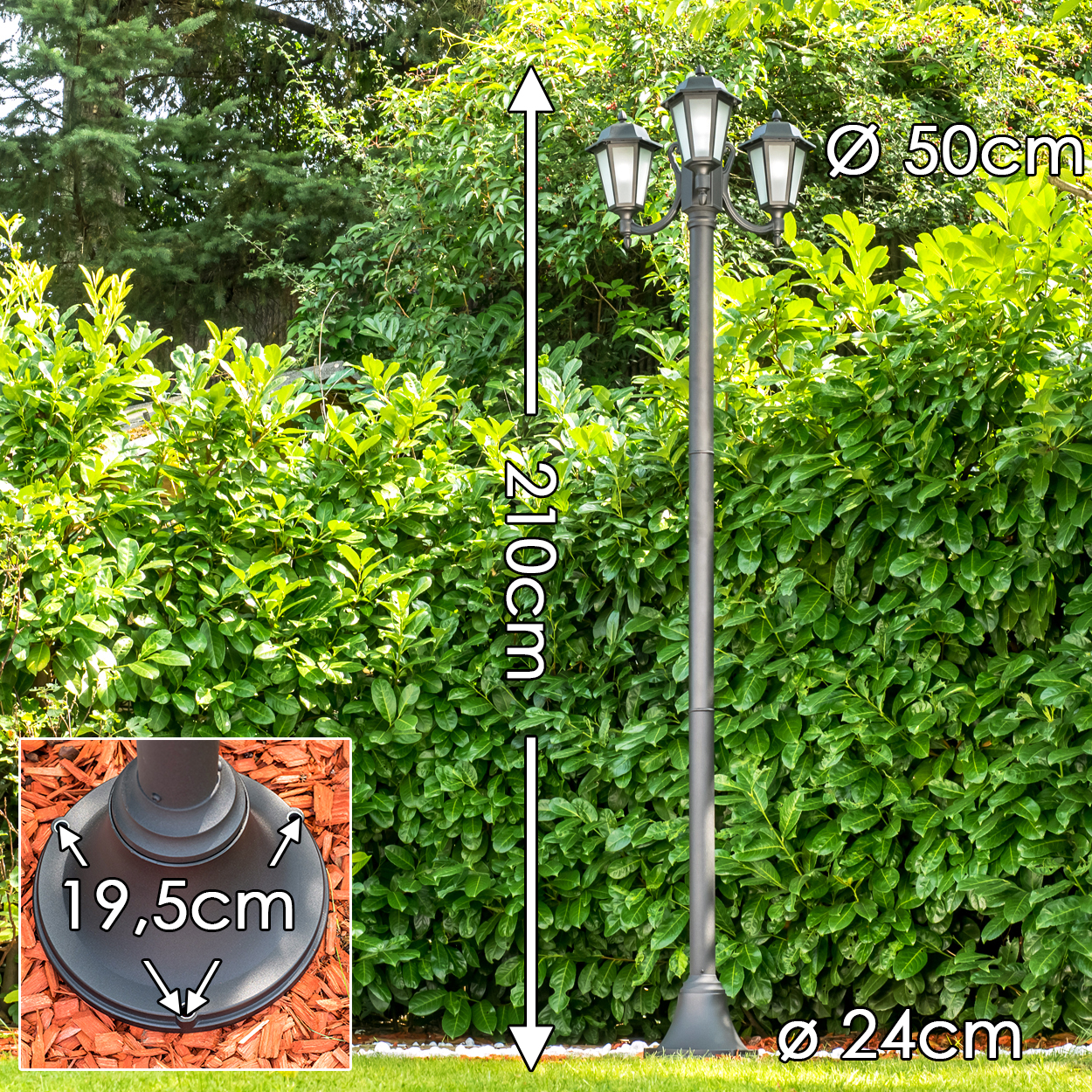 Ein dunkler Laternenpfahl mit drei Lichtern steht im Garten.