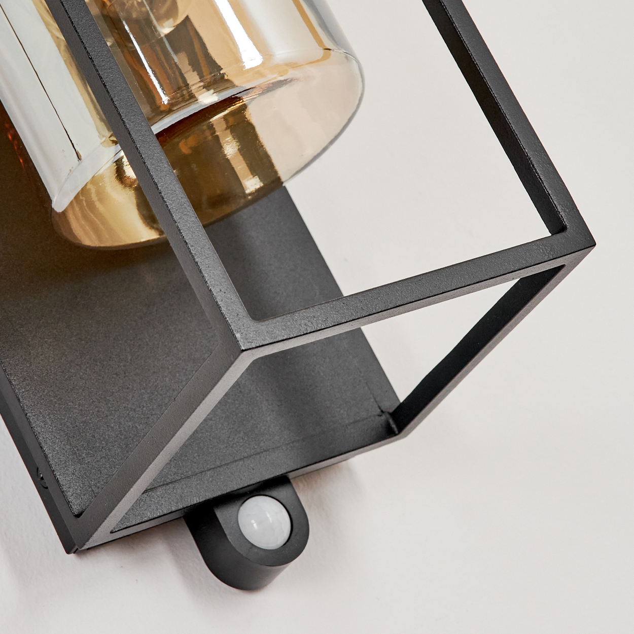 Moderne schwarze Wandleuchte mit bernsteinfarbenem Glas und Bewegungsmelder.