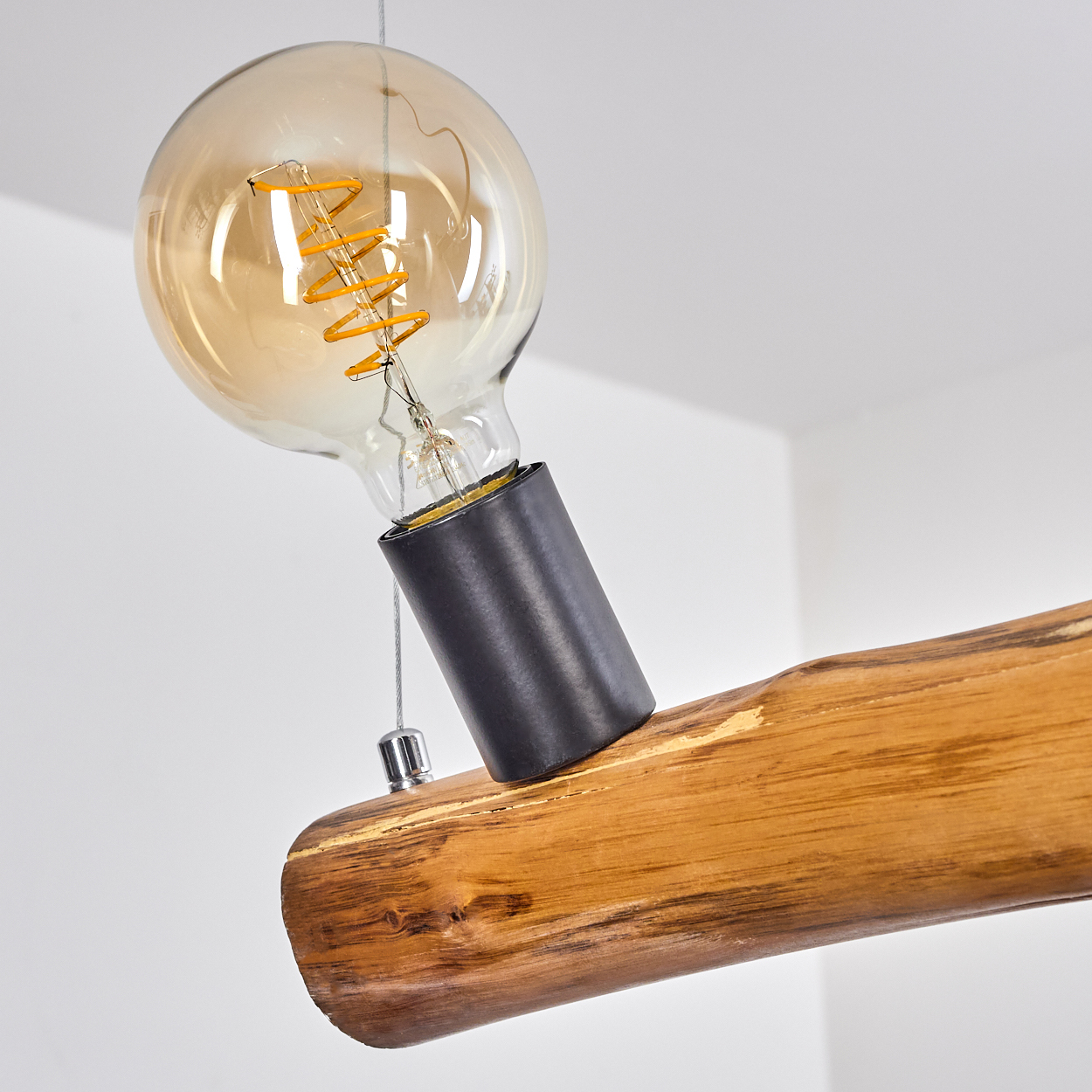 Eine große Edison-Glühbirne mit Spiralfilament an einem Holzstamm-Lampenkörper.