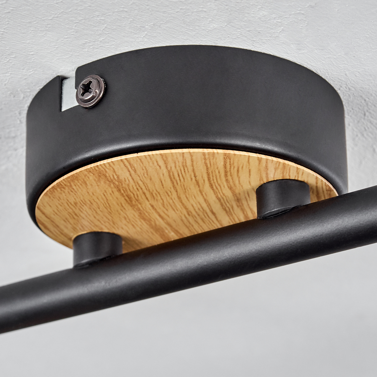 Schwarze Lampe mit Holzakzent, an weißer Decke montiert.
