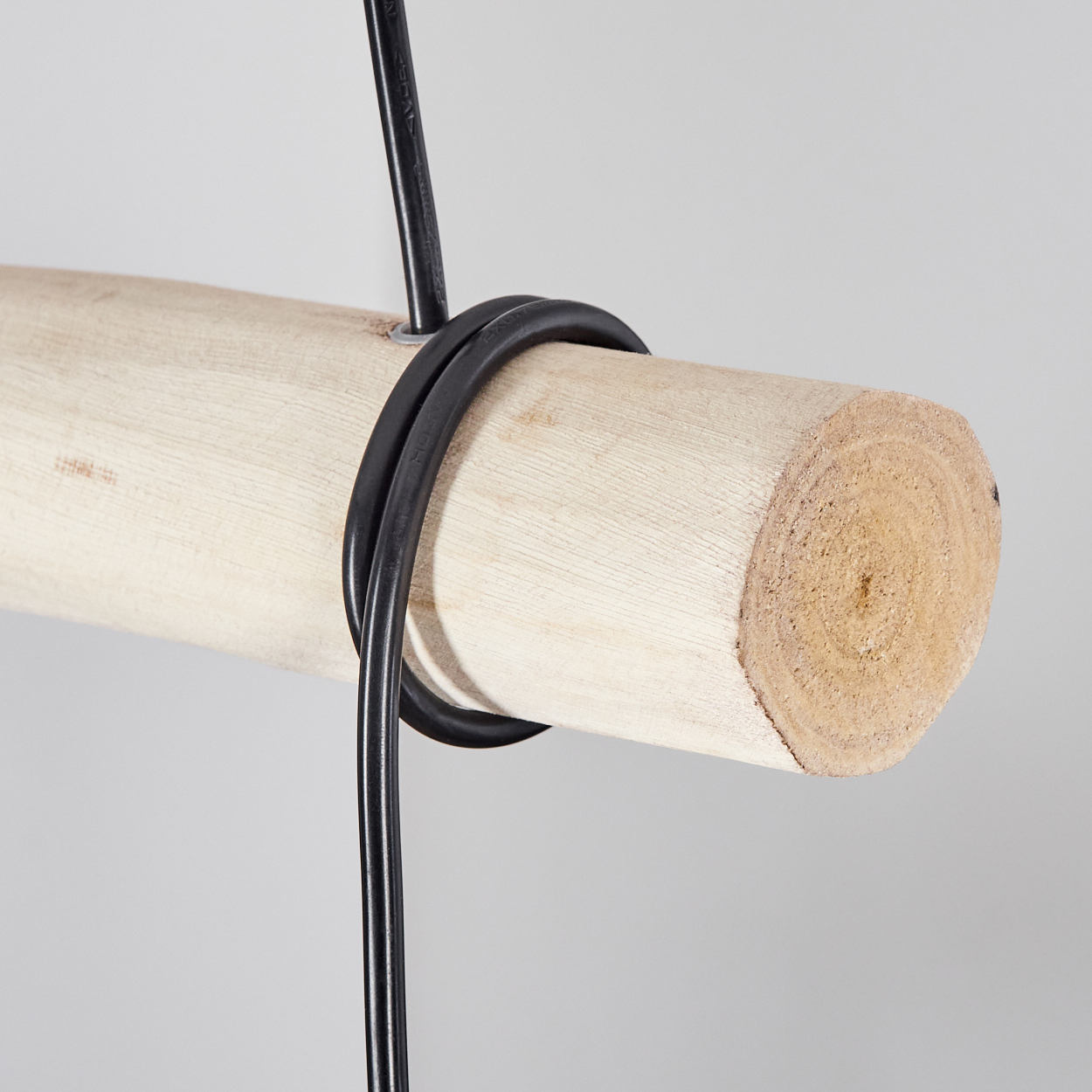 Ein Holzbalken mit einem schwarzen Kabel, das darum gewickelt ist.