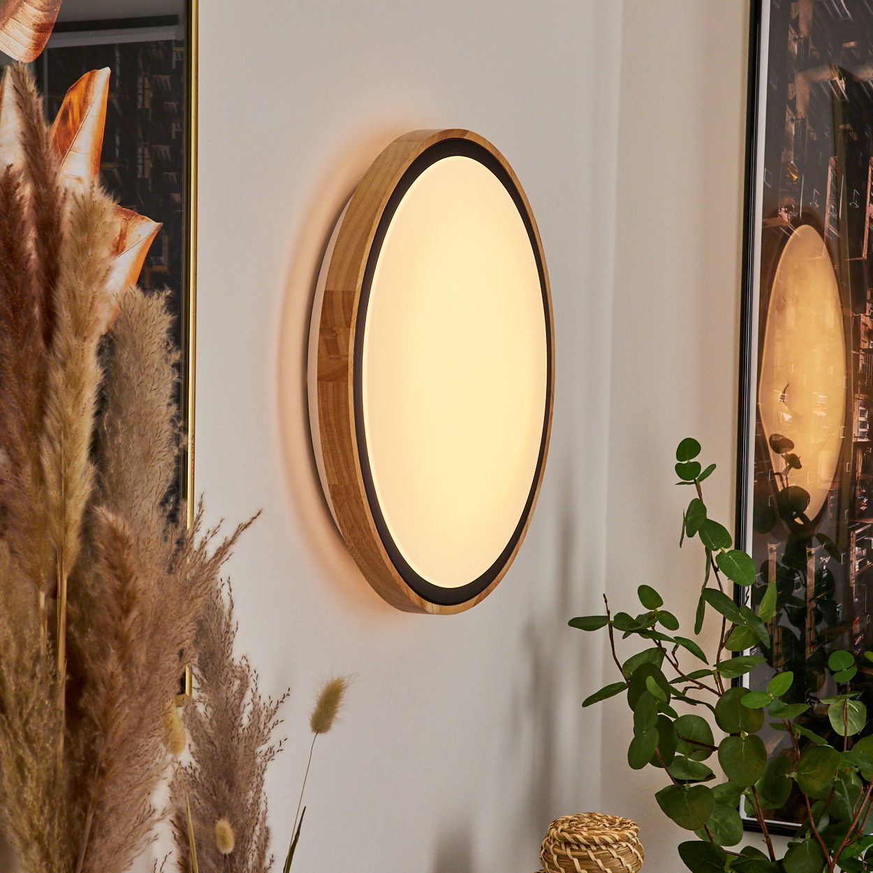 Ovales Holzlicht mit schwarzem Rand, beleuchtet, an der Wand neben Pflanzen.