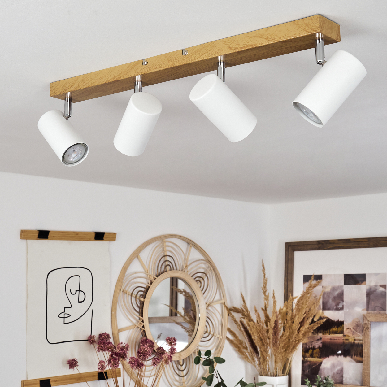 Vier weiße zylindrische Spots auf einem Holzbalken an der Decke.