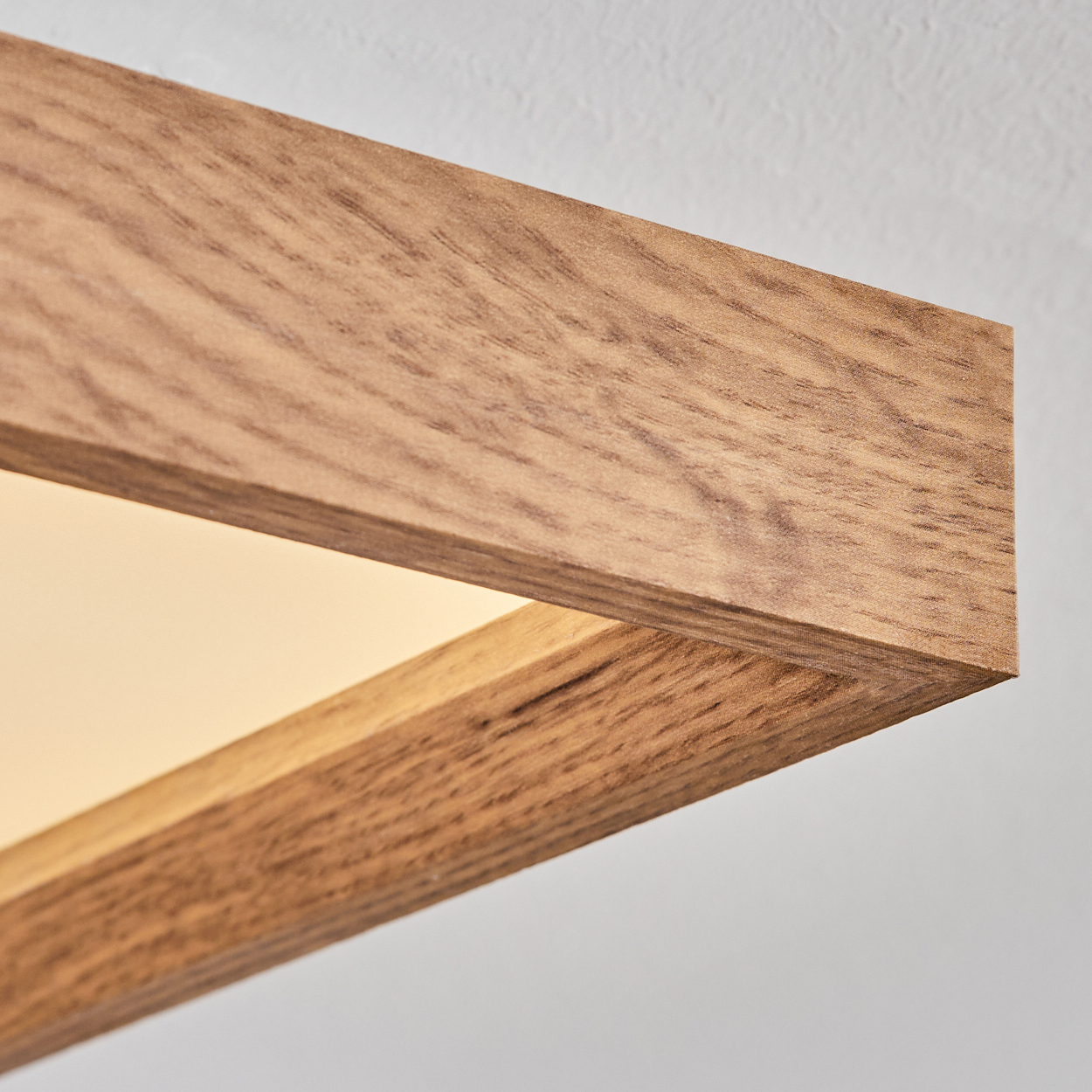 Ein Holzelement mit sichtbarer Maserung, das einen hellen, leuchtenden Hintergrund umrahmt.