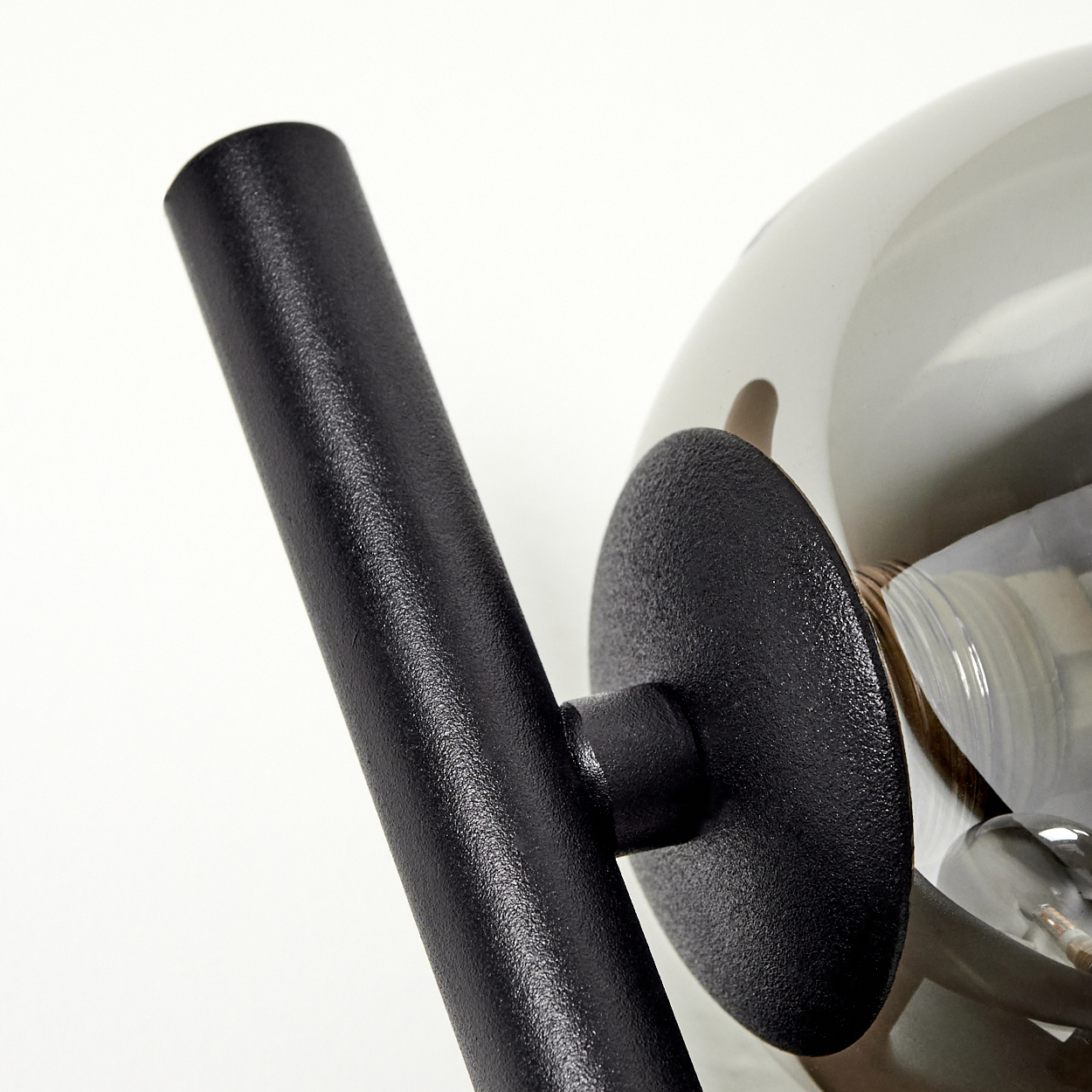 Nahaufnahme einer schwarzen Metalllampe mit einem rauchglasartigen Lampenschirm.