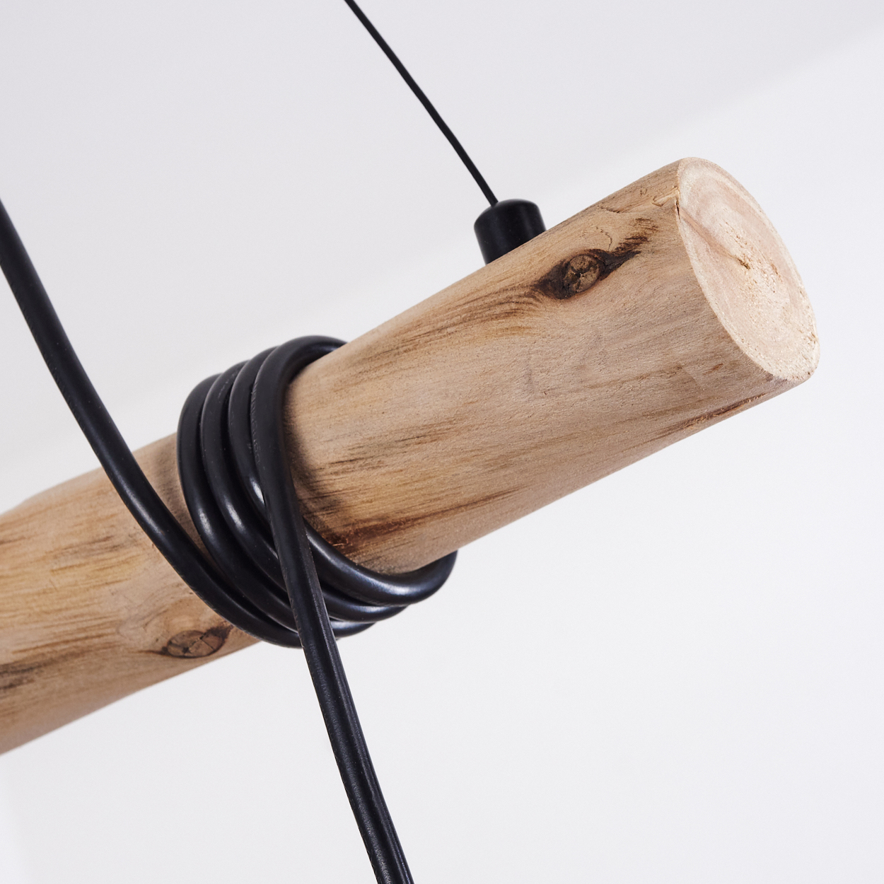 Ein Holzbalken mit einem schwarzen Kabel, das darum gewickelt ist, vor einem weißen Hintergrund.