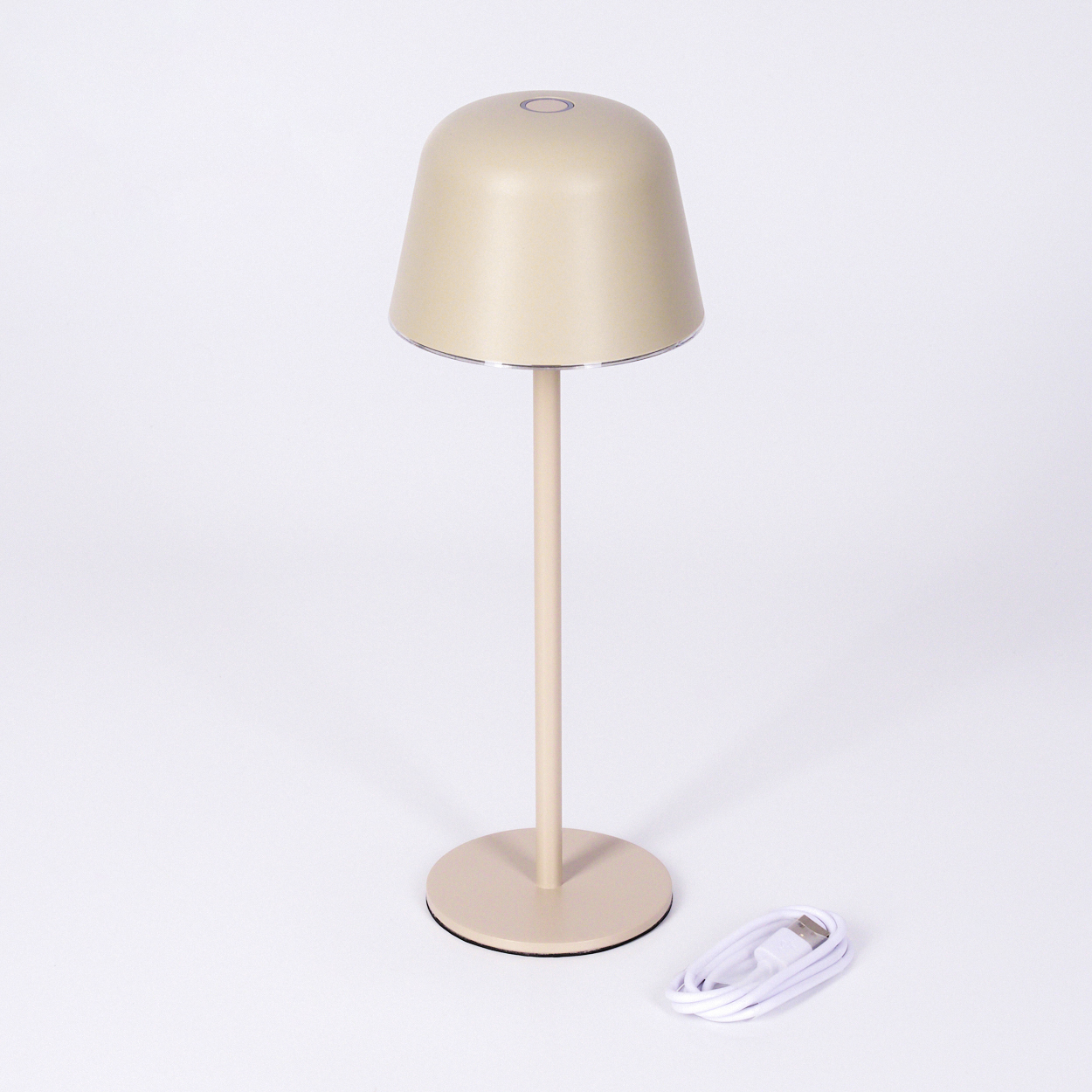Eine beige Schreibtischlampe mit einem runden Fuß und einem USB-Kabel daneben.