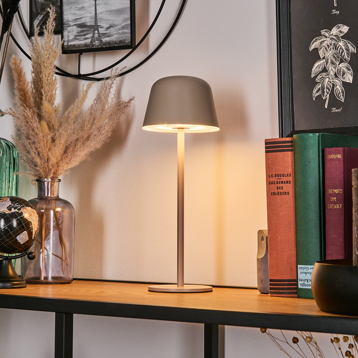 Graue Lampe auf einem Regal mit Büchern, Vase und Globus.