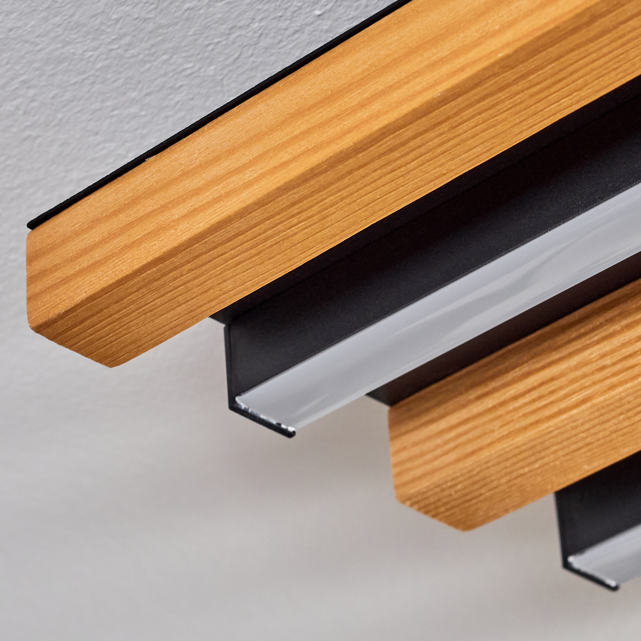 Holzbalken mit schwarzen Metallbefestigungen und Lichtstreifen an der Decke.