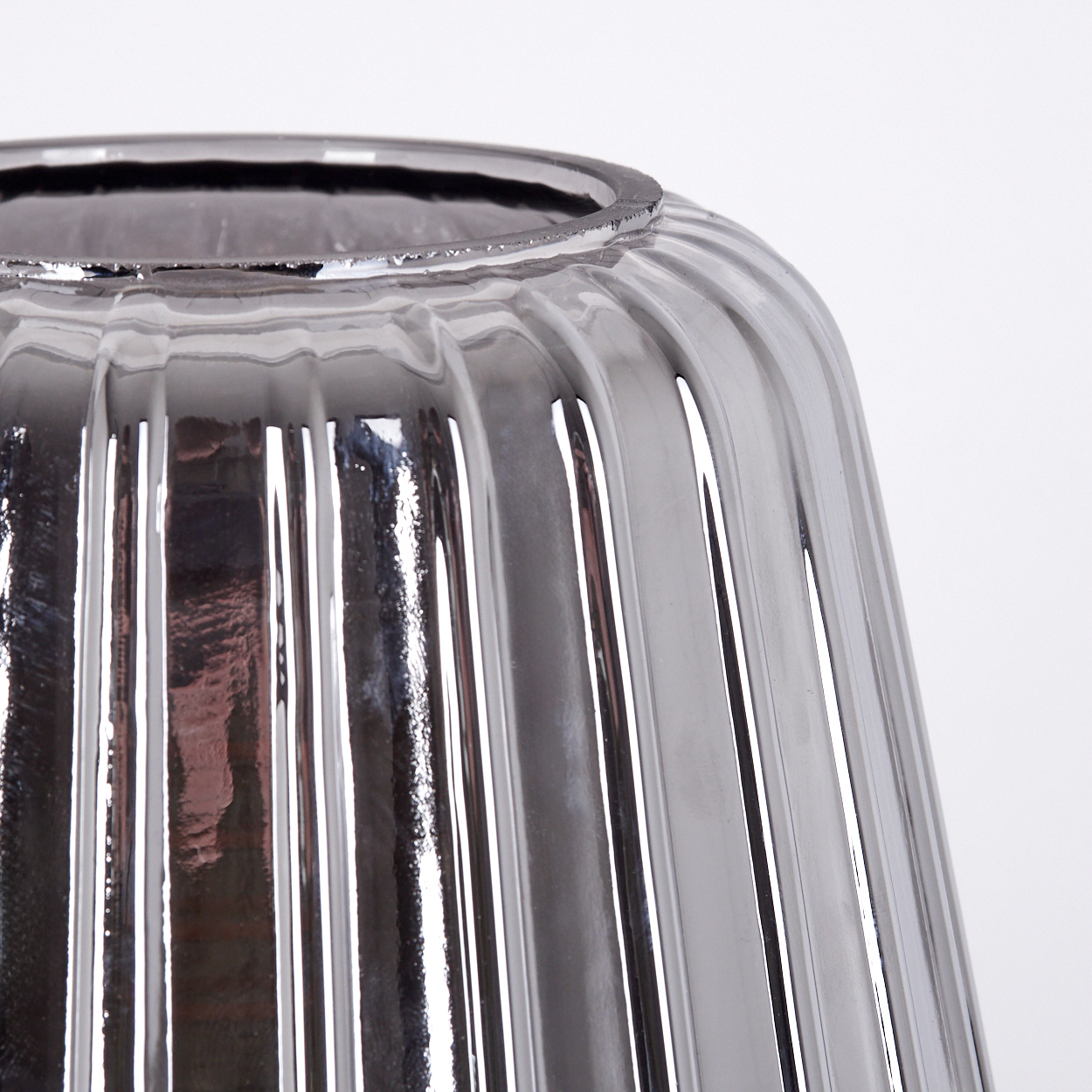Eine Nahaufnahme einer gerippten, grauen Glasvase mit reflektierender Oberfläche.