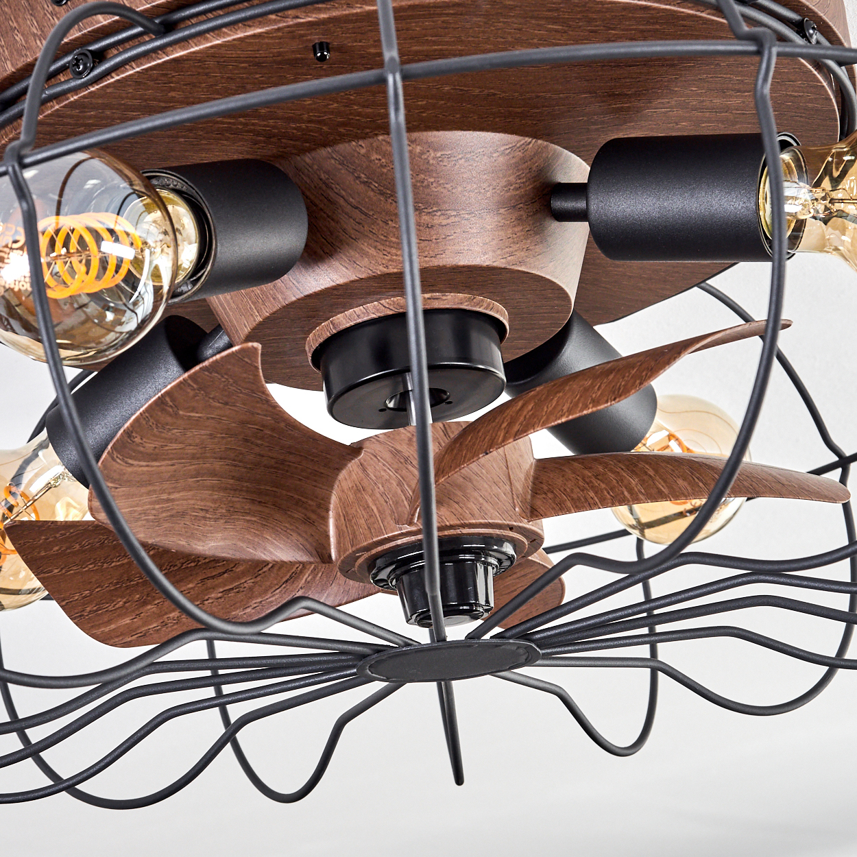 Deckenventilator mit Holzblättern, Glühbirnen und schwarzem Drahtkäfig.