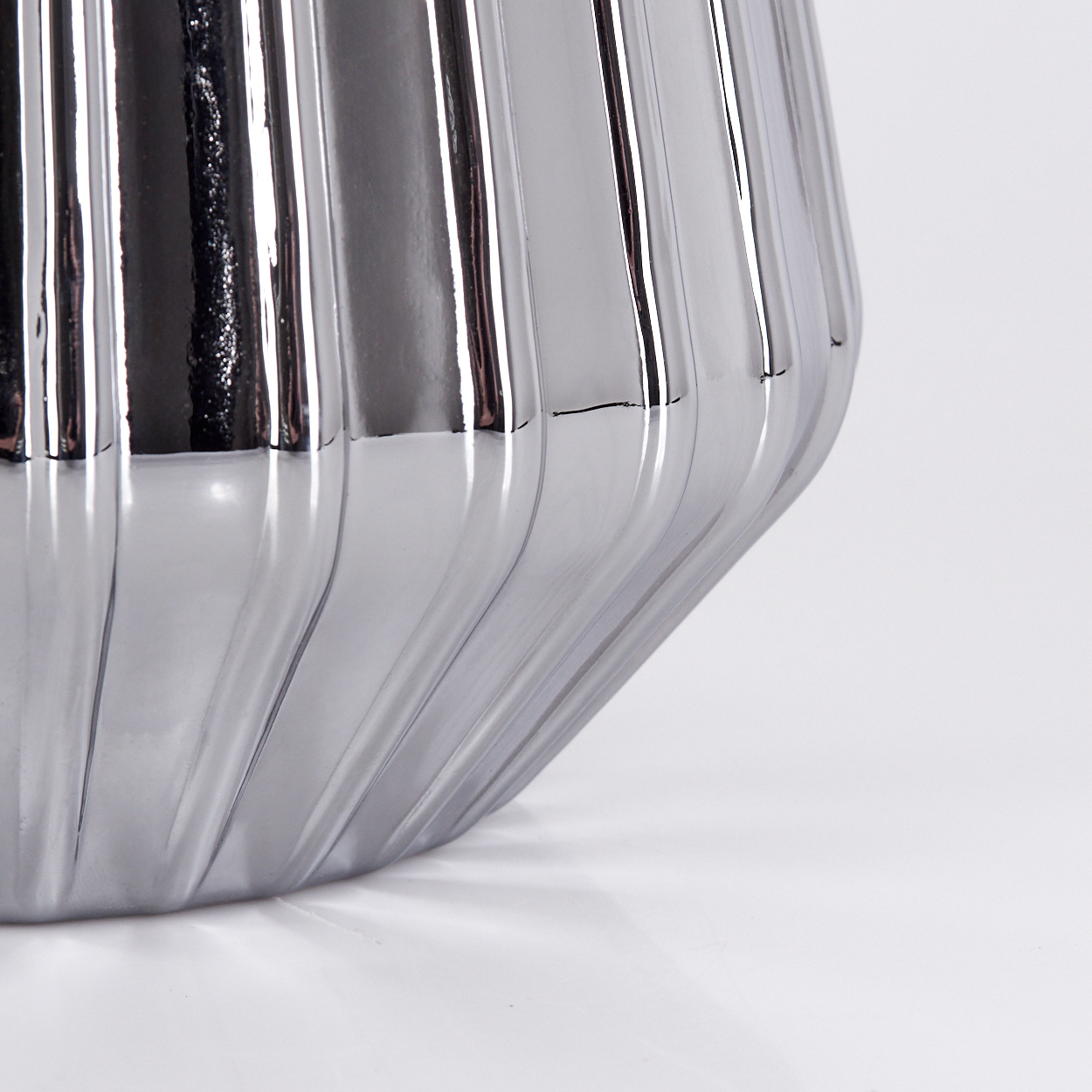 Eine silberne, gerippte Vase oder ein Topf auf weißem Hintergrund.