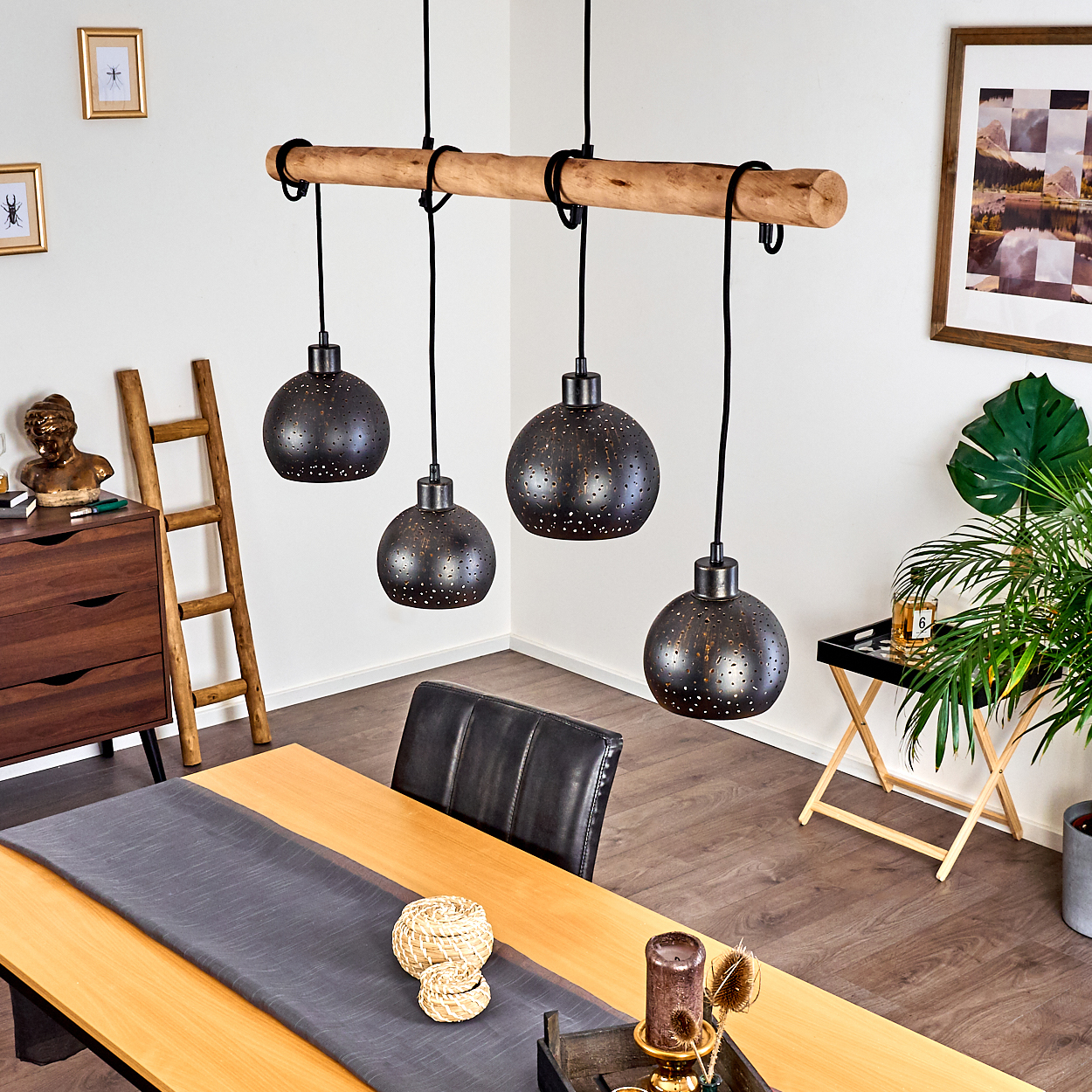 Hängelampe aus Holz mit vier dunklen, perforierten Schirmen über einem Holztisch.