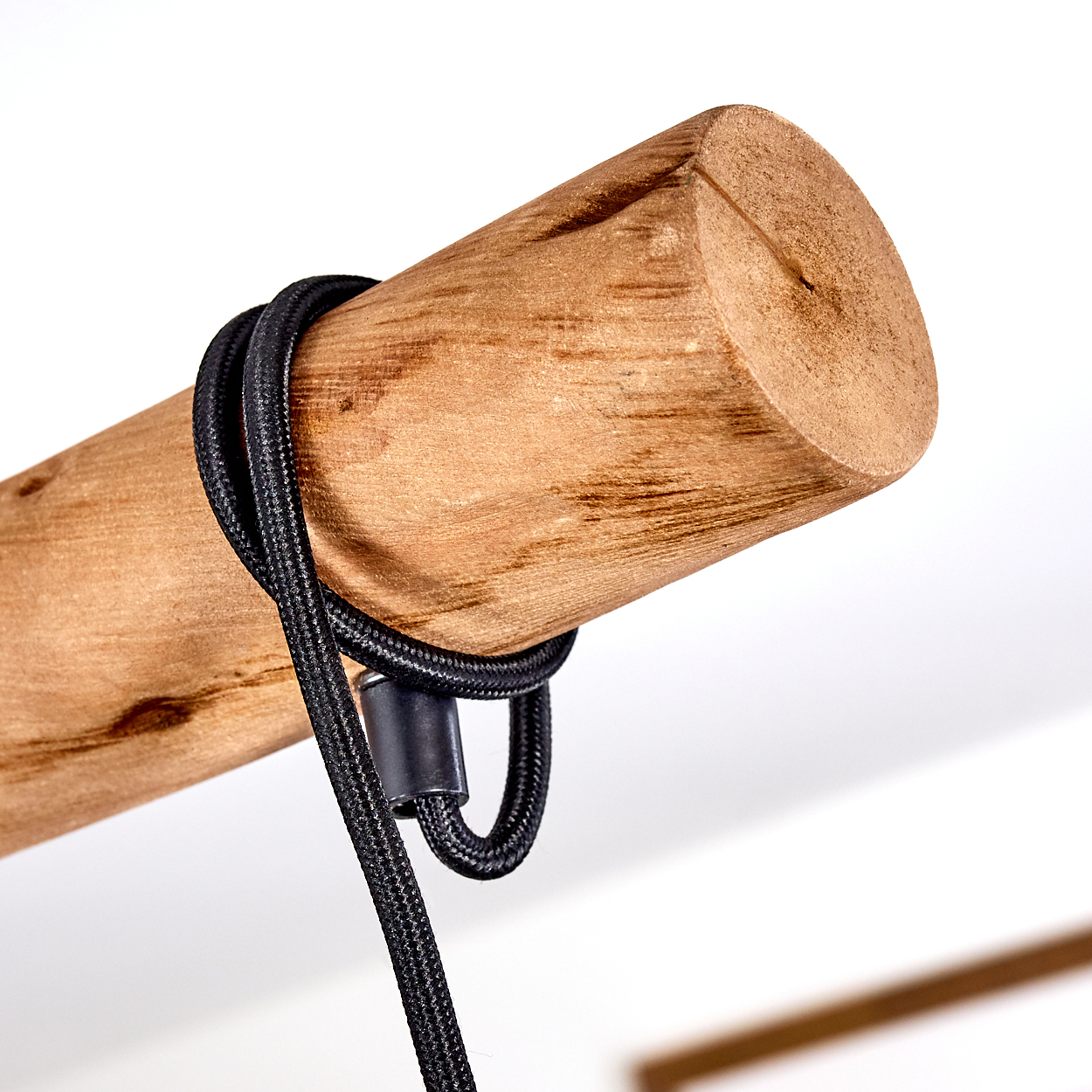 Ein schwarzes Kabel ist um ein Stück unbehandeltes Holz gewickelt.