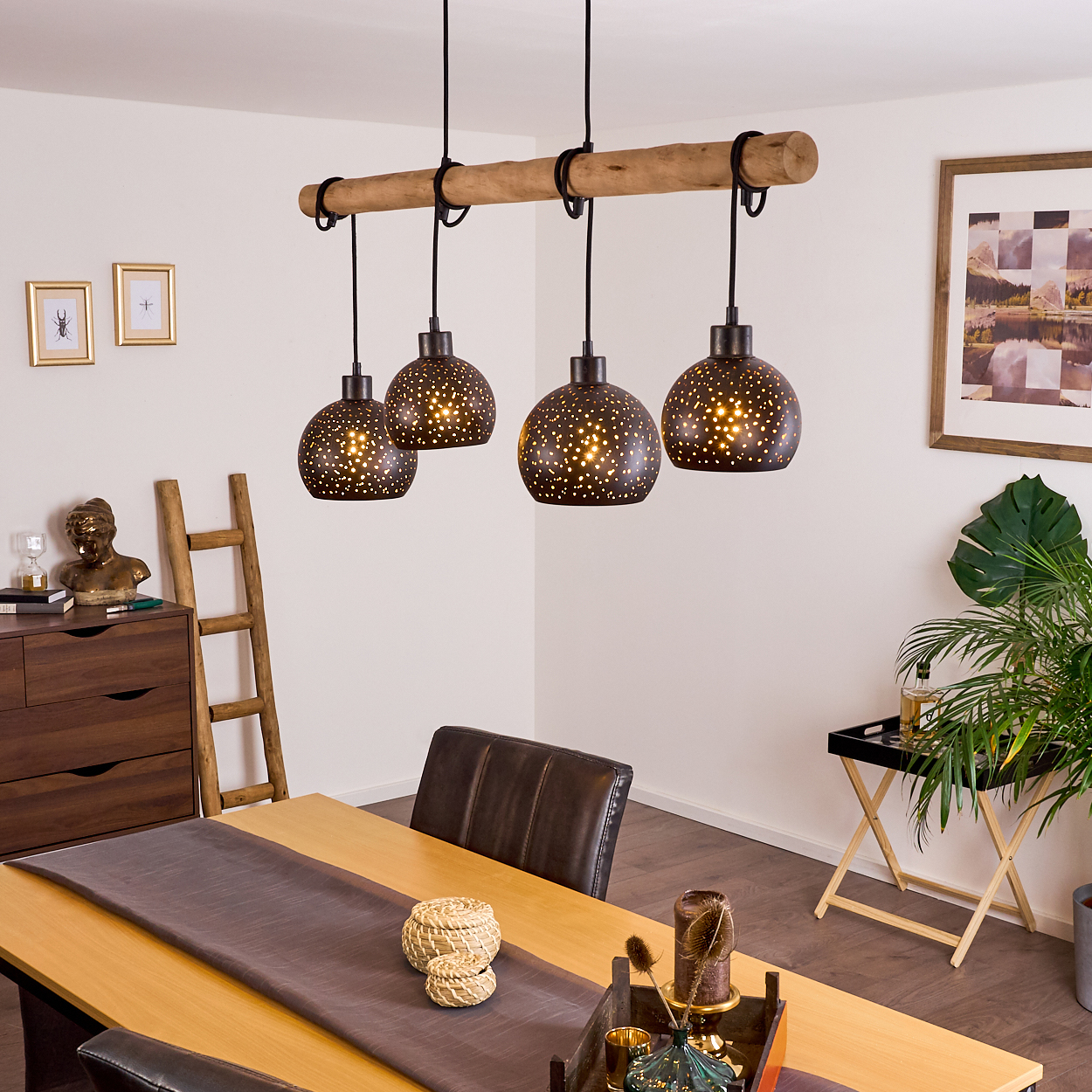 Holzbalkenlampe mit vier Lochmusterschirmen über Holztisch mit braunen Stühlen.
