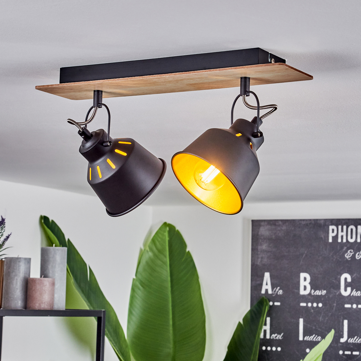 Zwei schwarze Deckenstrahler mit Holzdetail und gelbem Licht hängen.