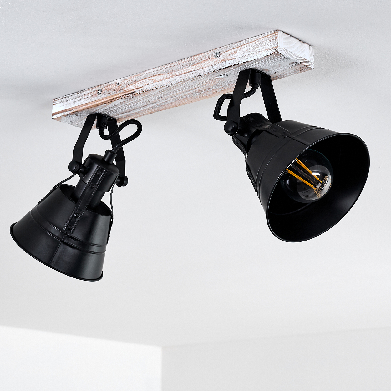 Zwei schwarze Strahler an einer Holzschiene an der Decke montiert.
