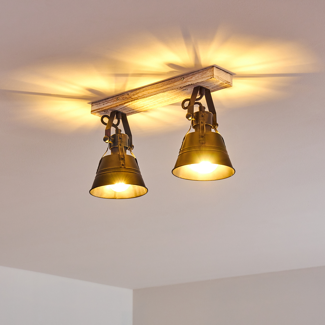 Zwei industrielle Lampen hängen an einem Holzbrett von der Decke.